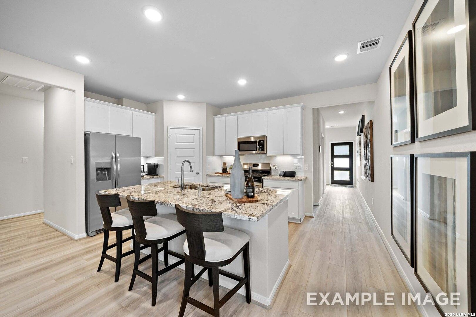Modern kitchen with granite island and white cabinets in The San Marcos F floor plan, Rayburn Valley, San Antonio, Texas.
