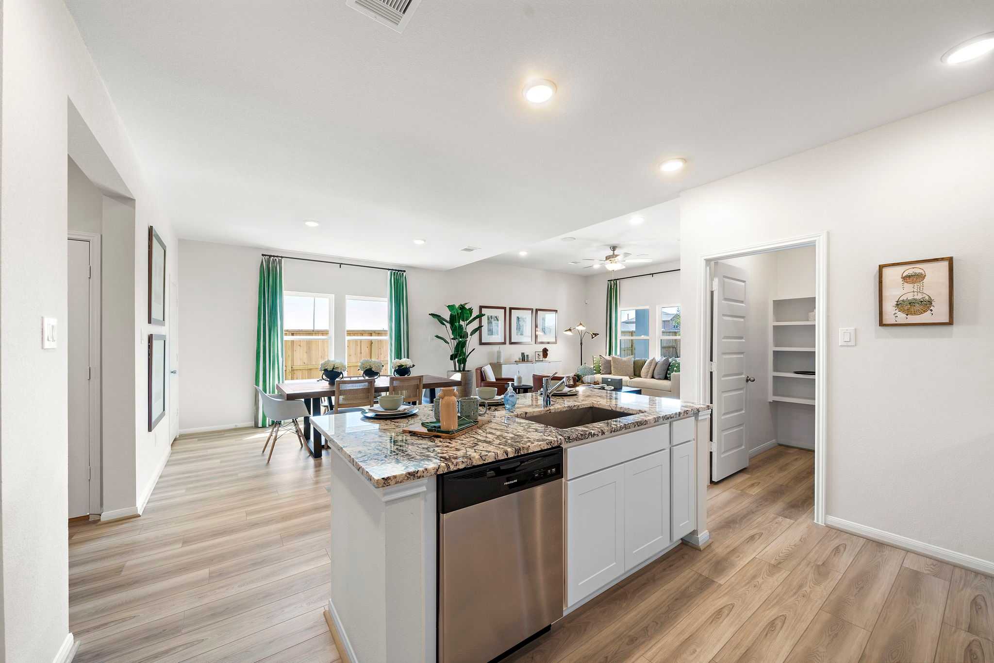 Open-concept kitchen dining area at River Ranch Meadows in Dayton Texas with granite island, hardwood floors, and large windows