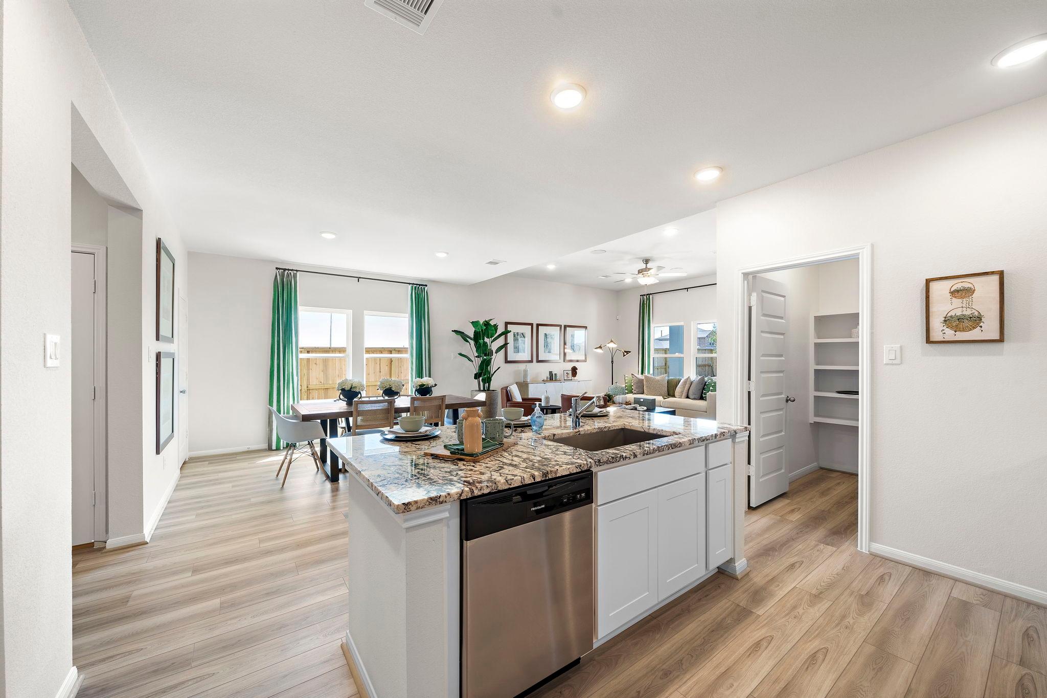 Open-concept kitchen dining area at River Ranch Meadows in Dayton Texas with granite island, hardwood floors, and large windows