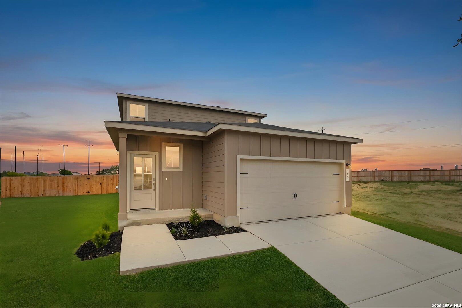 Modern 2-story beige home with 2-car garage, front entry, and landscaped green yard at sunset in Agave, San Antonio, Texas - Davidson Homes Sabine A
