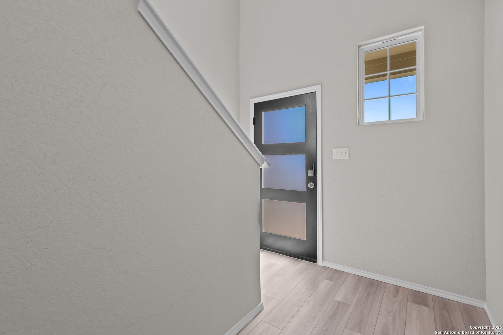 Modern staircase with white railing and frosted glass door in Davidson Homes The Trinity D, 4-bedroom home, San Antonio
