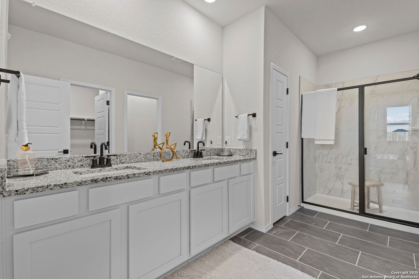 Elegant master bathroom with double quartz vanity, frameless glass shower, and white shaker cabinets in Davidson Homes The Douglas C, Seguin, Texas
