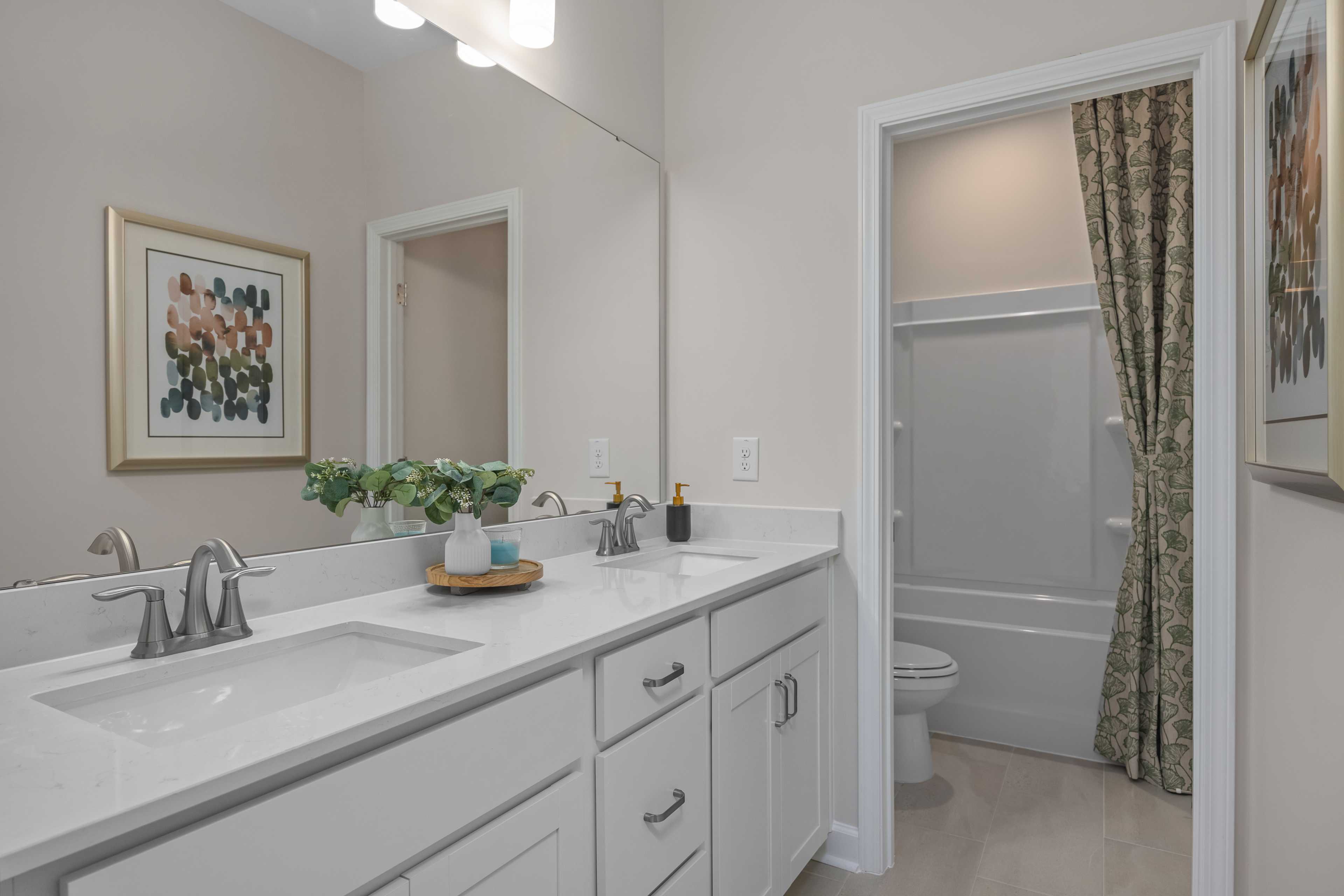 Spacious modern bathroom at Sage on North Main in Wake Forest NC with double vanity, white cabinets and tub shower combo