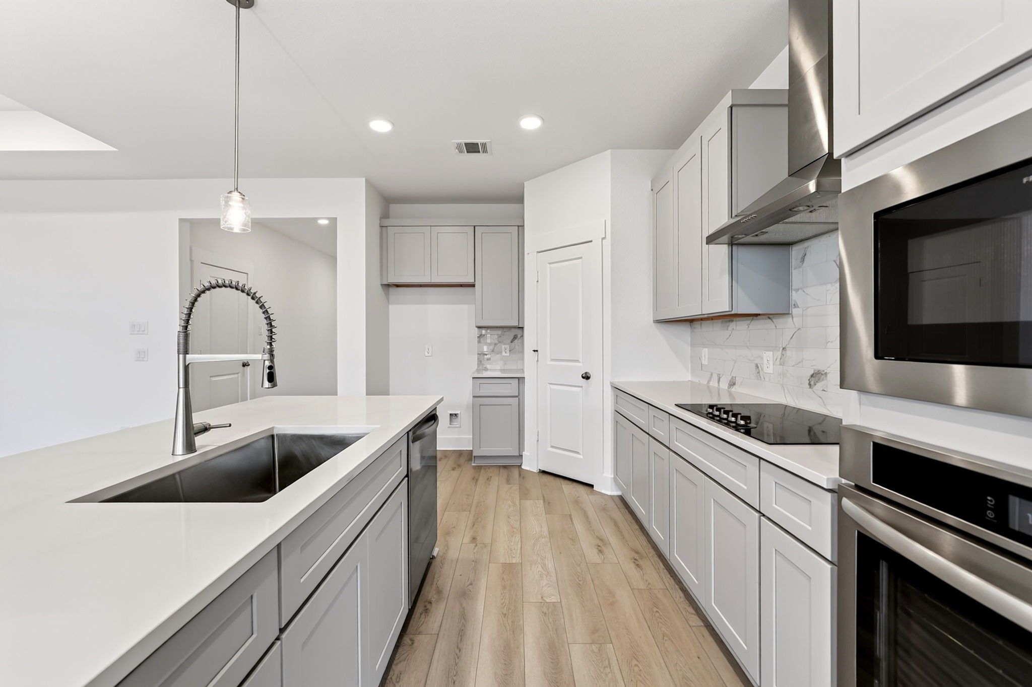 Modern kitchen with gray cabinetry, white quartz island, and stainless appliances in Davidson Homes' The Holly F, Josephine, Texas