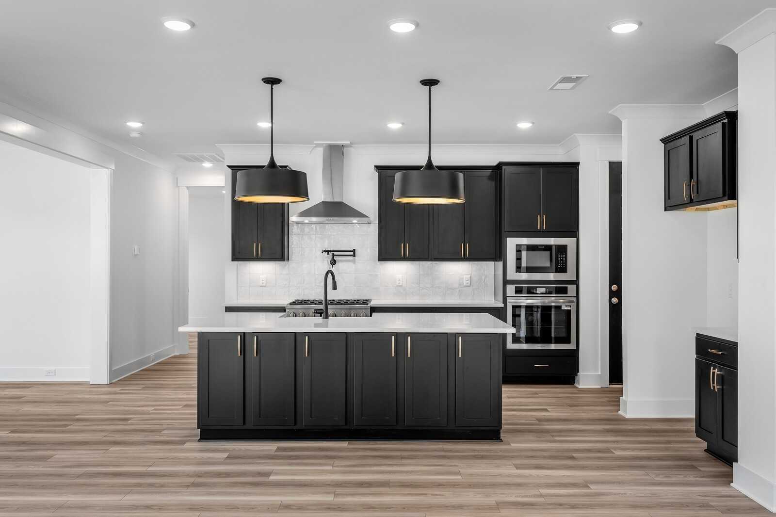 Modern kitchen with black cabinets, white quartz island, pendant lights, and double ovens in Davidson Homes The Hathaway, Murfreesboro, TN