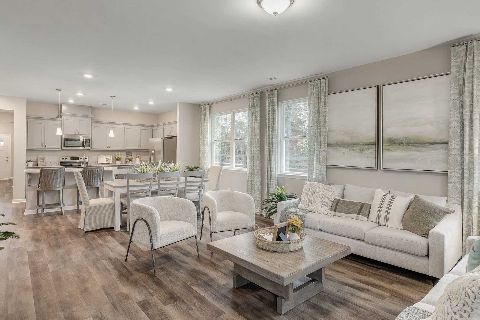 Spacious open-concept kitchen and living room in Carroll Green, Harvest Alabama with white cabinetry, hardwood floors, and large windows