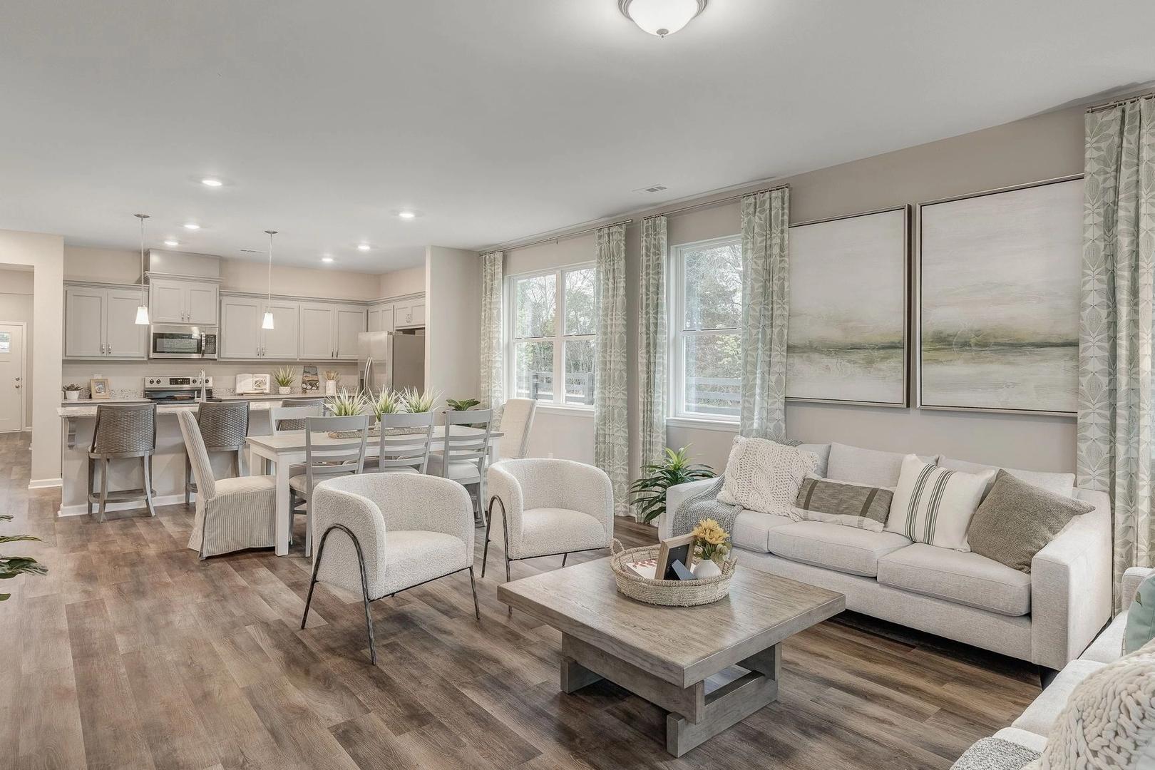 Spacious open-concept kitchen and living room in Carroll Green, Harvest Alabama with white cabinetry, hardwood floors, and large windows