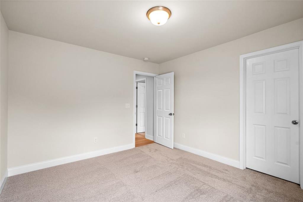 Cozy empty bedroom with beige walls, plush carpet, white doors, and soft ceiling light in Davidson Homes The Hickory B at Wehunt Meadows, Hoschton