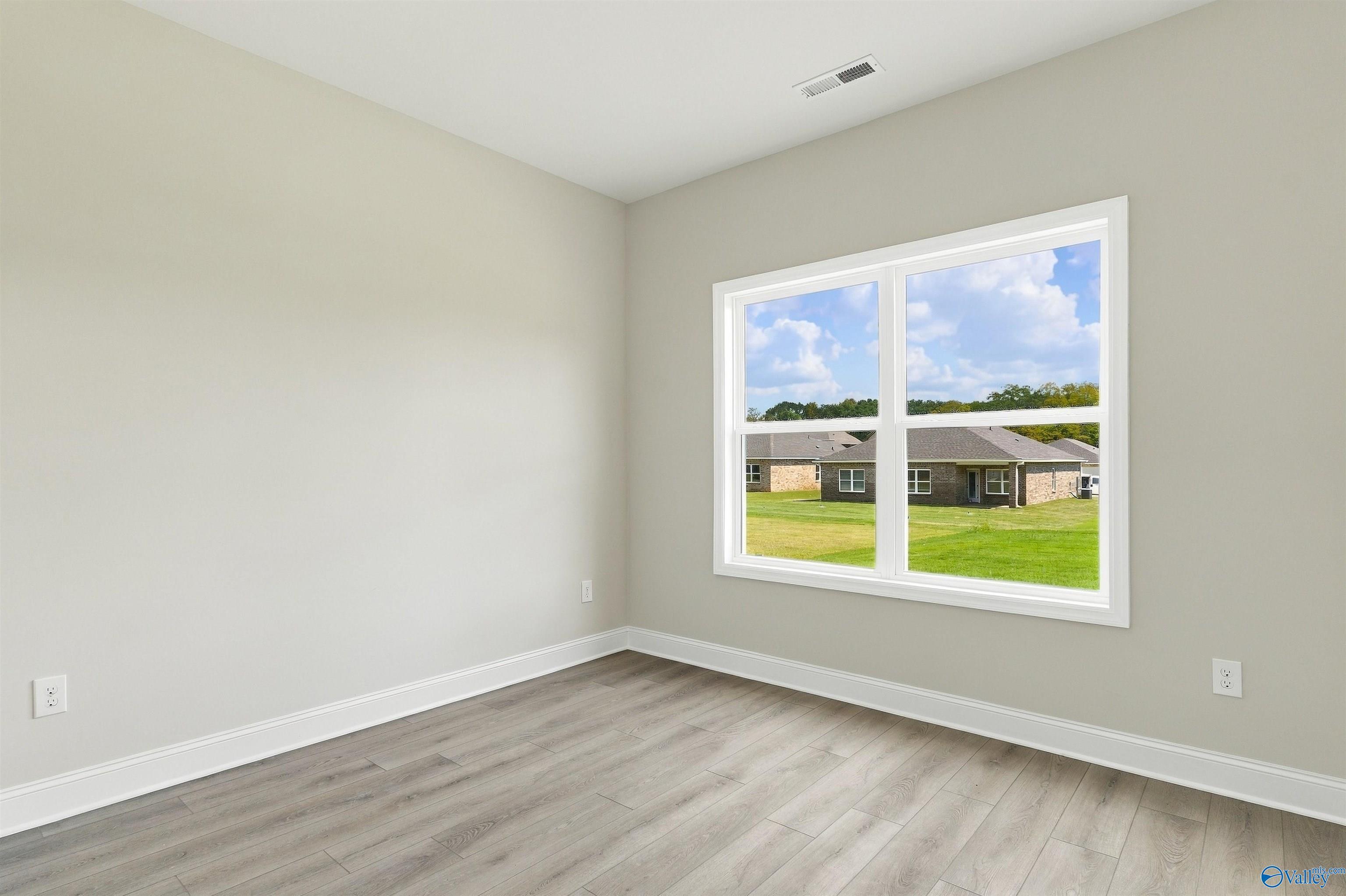 Bright empty bedroom with luxury vinyl plank flooring and large window overlooking backyard in Davidson Homes The Shelby A, Athens