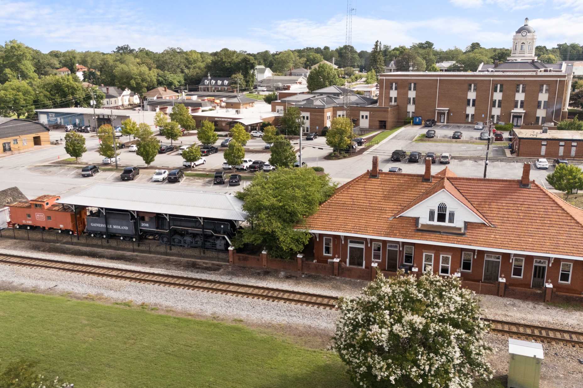 Historic Winder Georgia train depot with red roof, vintage orange locomotive, brick courthouse, and tree-lined downtown near Lake Shore