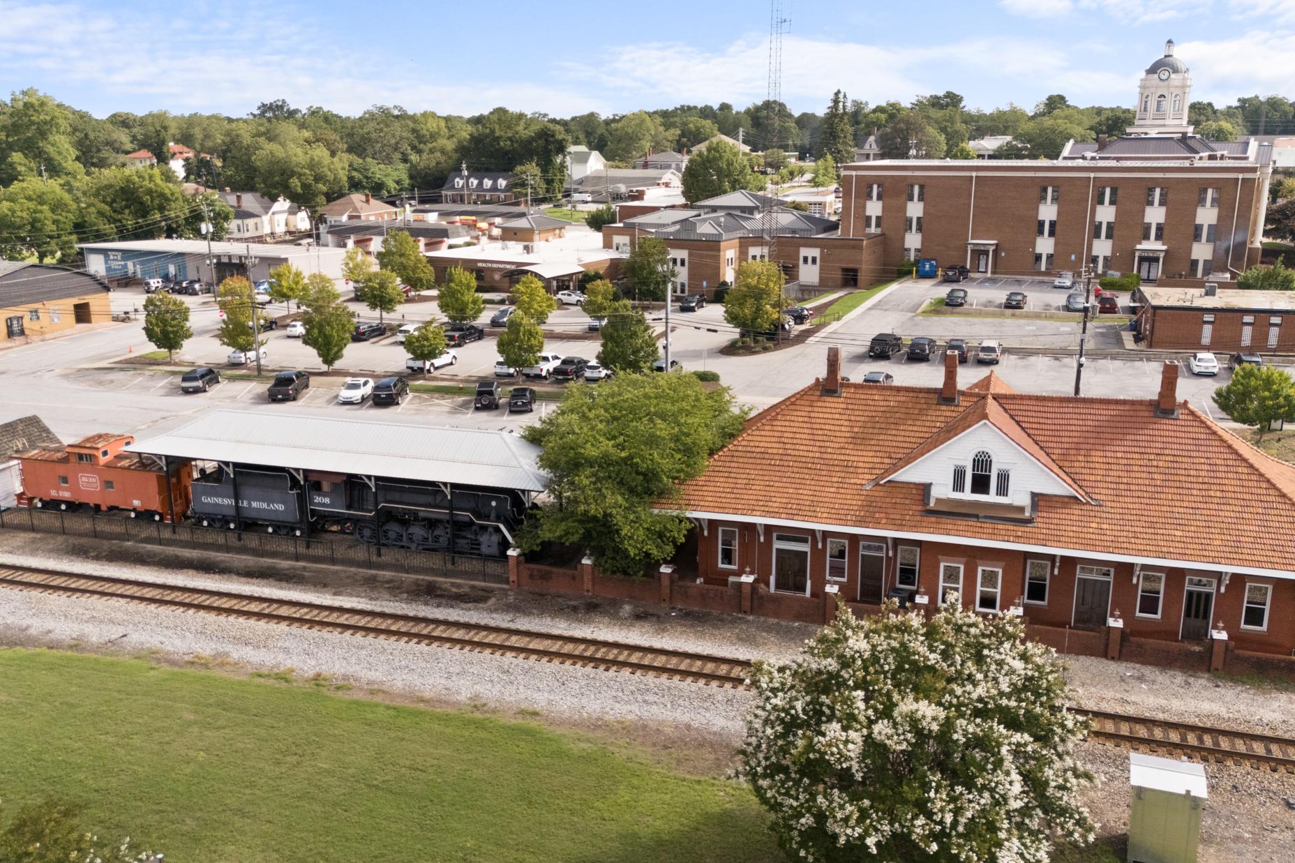 Historic Winder Georgia train depot with red roof, vintage orange locomotive, brick courthouse, and tree-lined downtown near Lake Shore