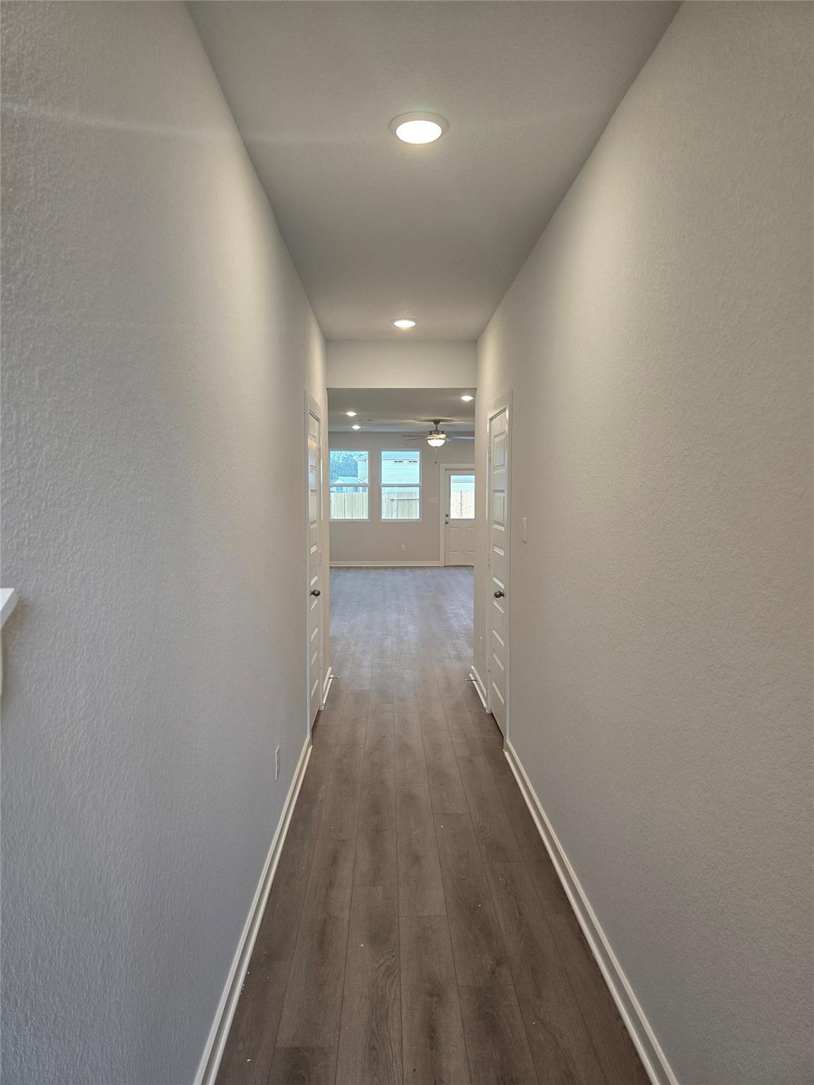Long hallway with wood-tone flooring, gray walls, and recessed lights in The Brazos E 5-bedroom home, Cleveland, Texas