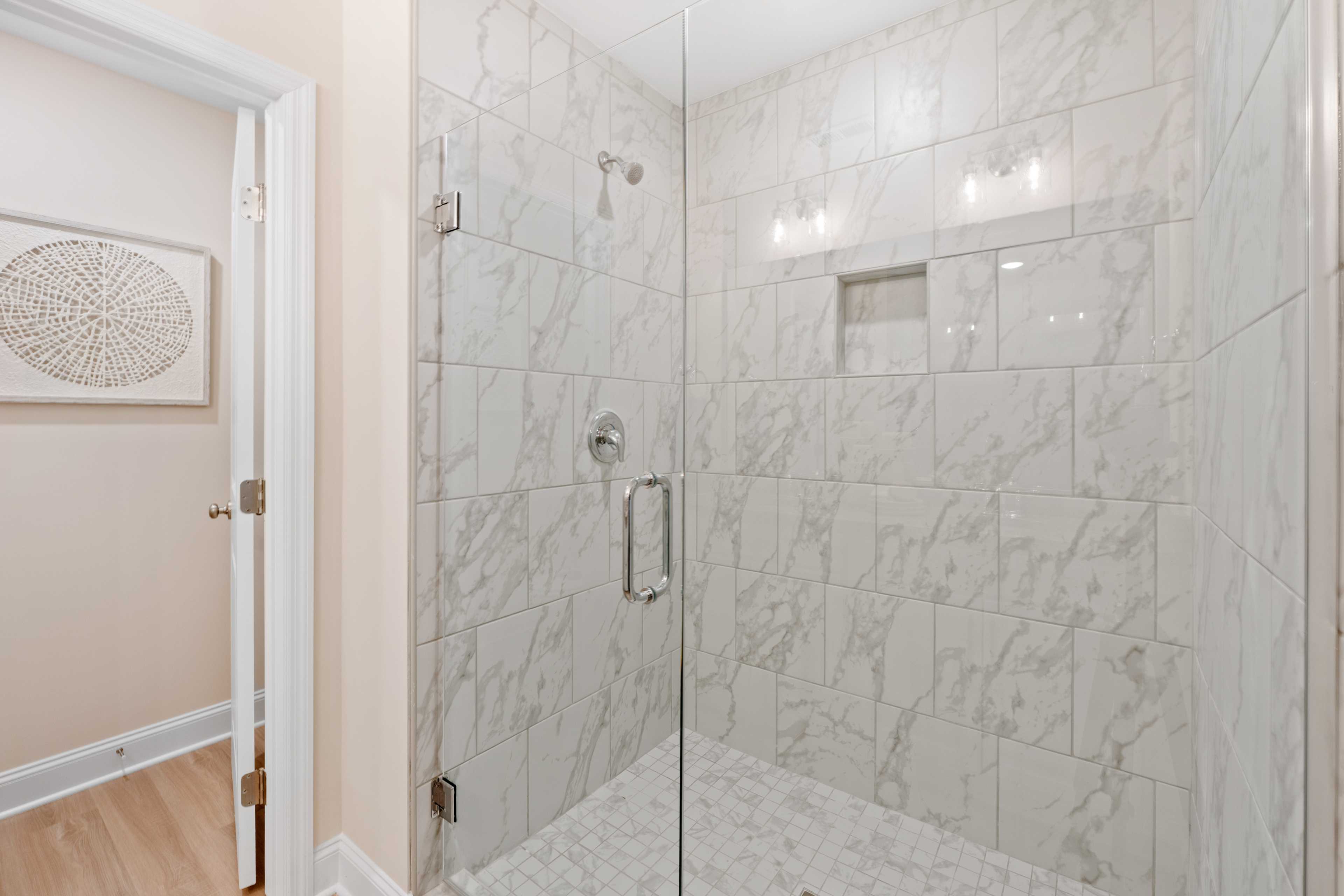 Luxurious white marble walk-in shower with frameless glass door at Pavilion in Huntsville, Alabama