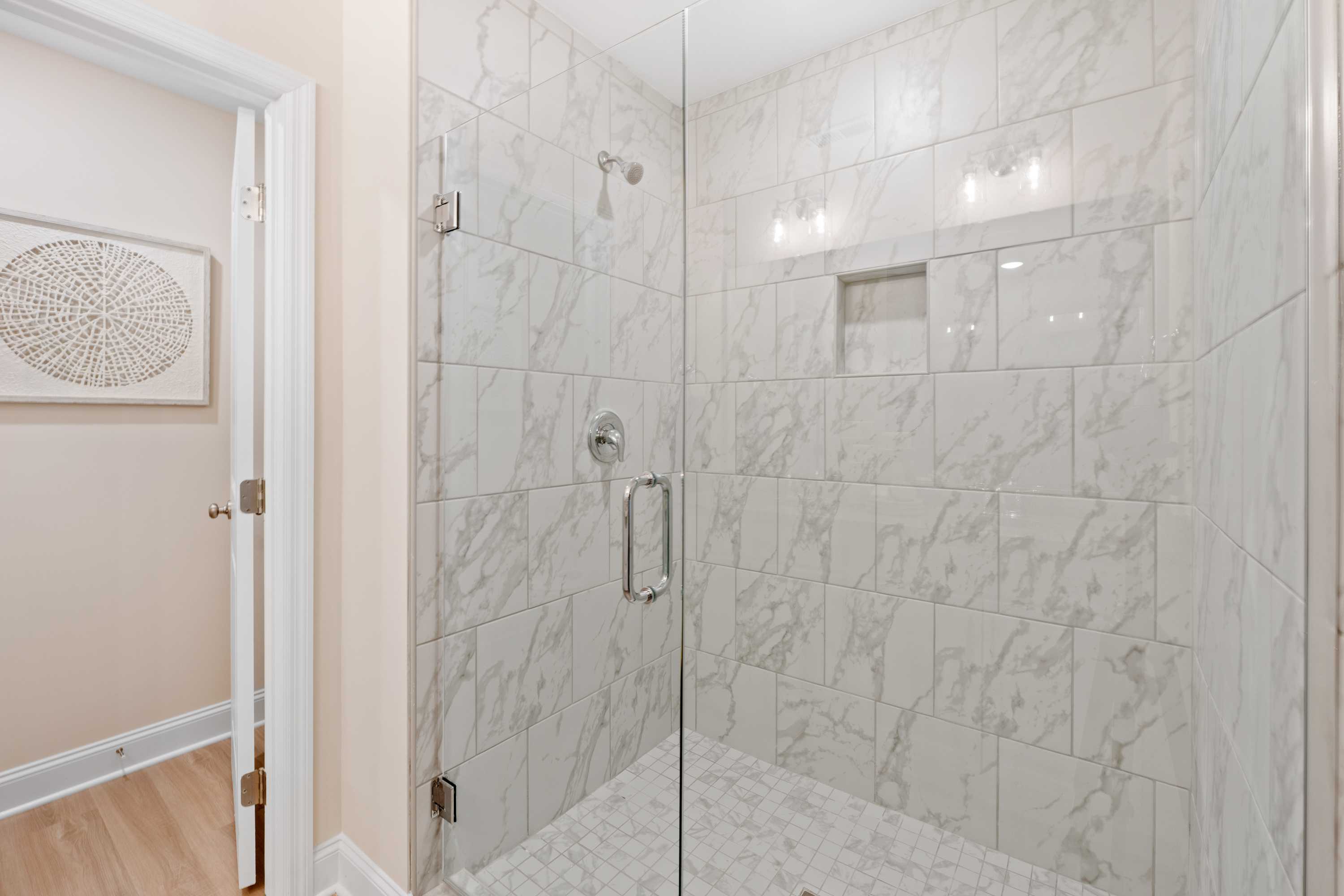 Luxurious white marble walk-in shower with frameless glass door at Pavilion in Huntsville, Alabama