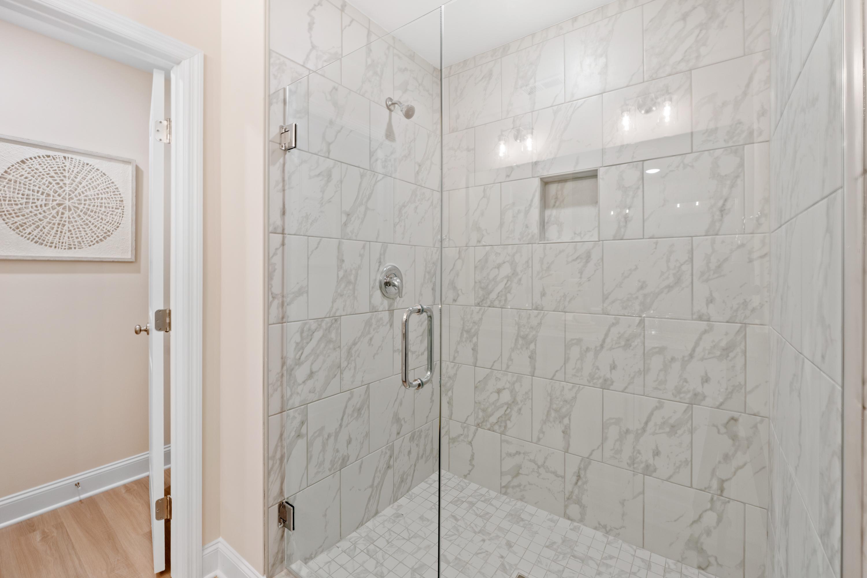 Luxurious white marble walk-in shower with frameless glass door at Pavilion in Huntsville, Alabama