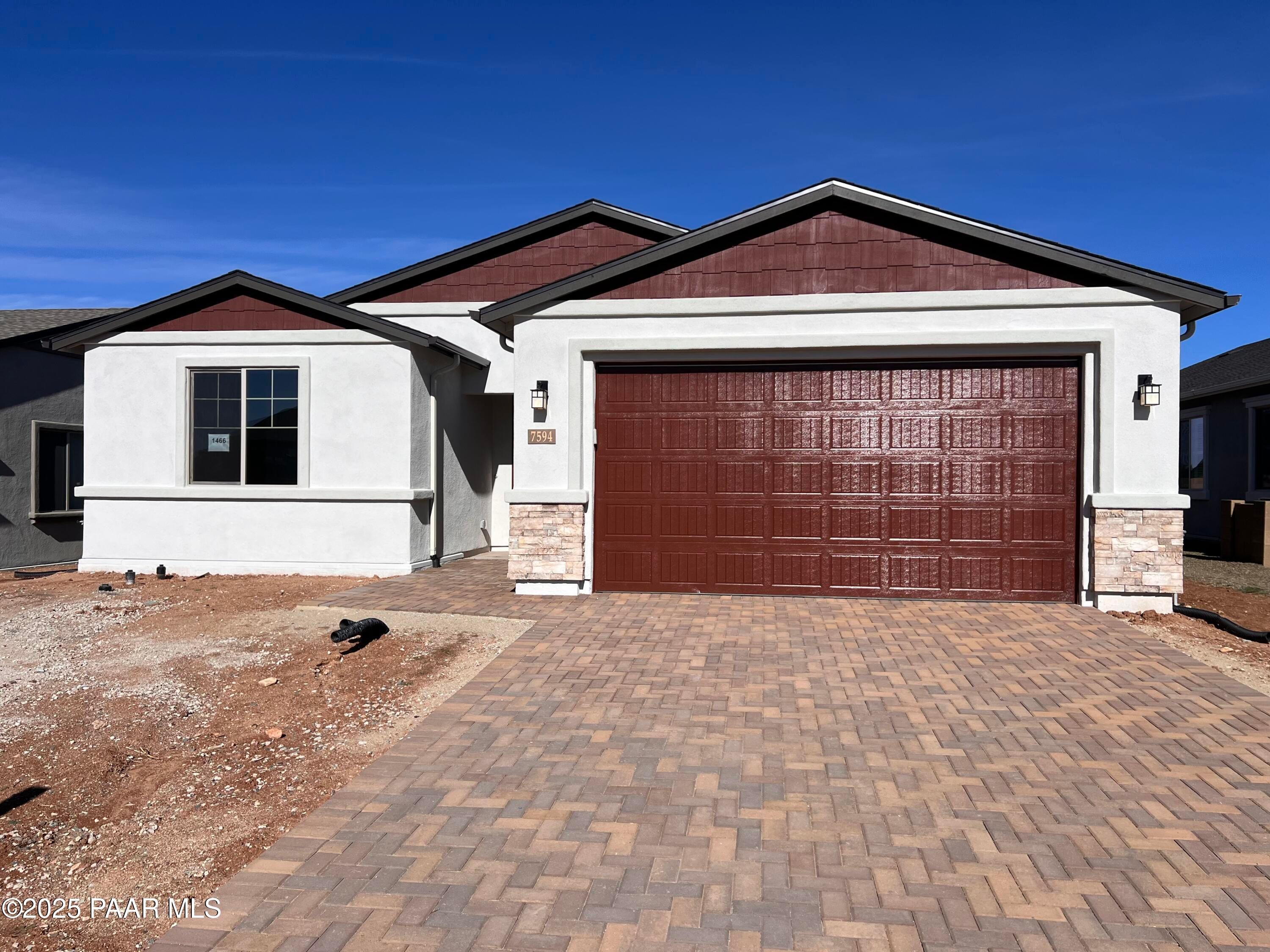 Single-story Davidson Homes Inspiration A with beige stucco, stone accents, red 3-car garage, paver driveway in Prescott Valley, AZ