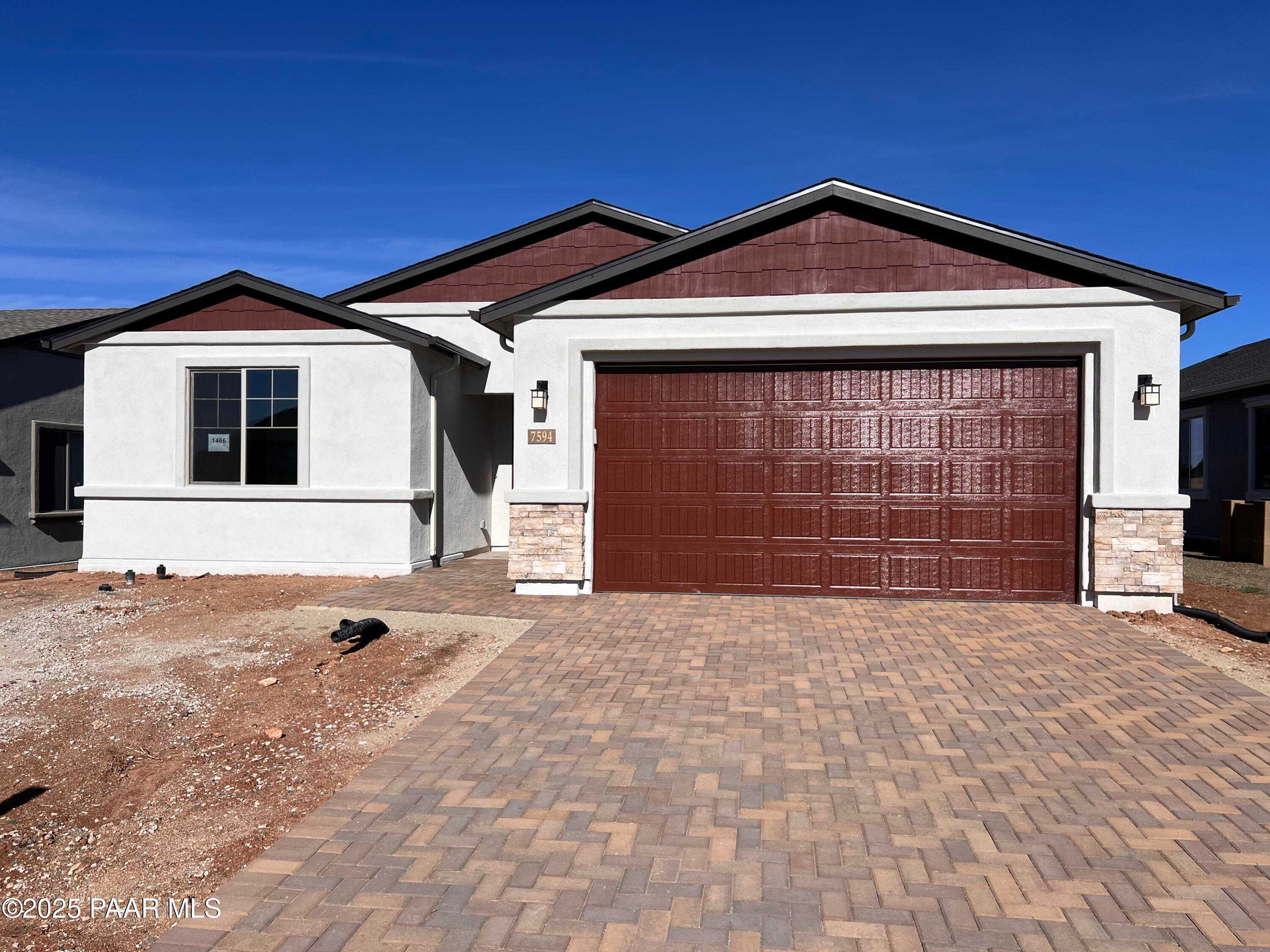 Single-story Davidson Homes Inspiration A with beige stucco, stone accents, red 3-car garage, paver driveway in Prescott Valley, AZ