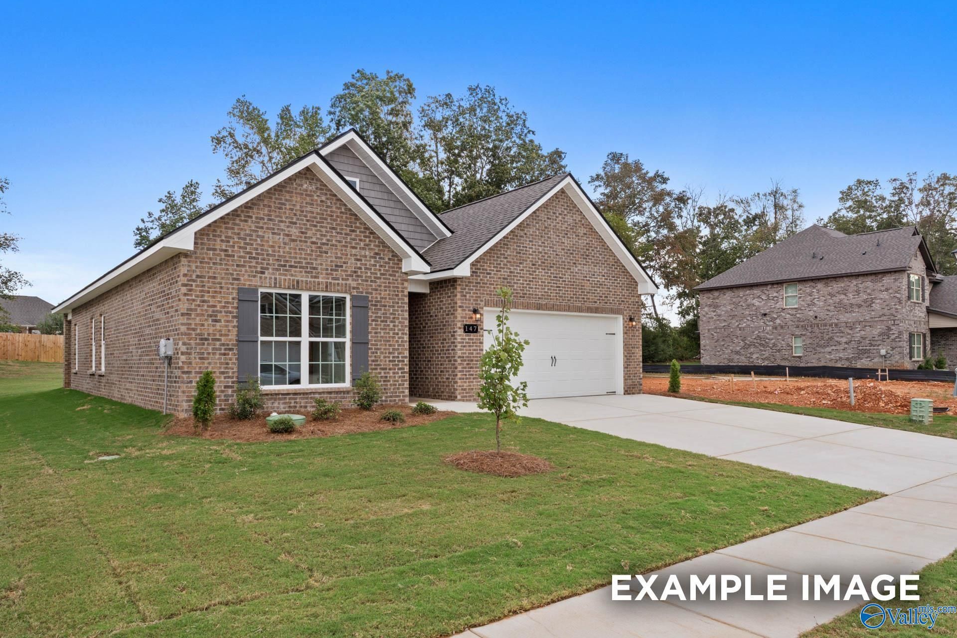 Modern brick ranch home with 2-car garage, white trim, and landscaped front yard in Wood Trail, Toney, Alabama by Davidson Homes