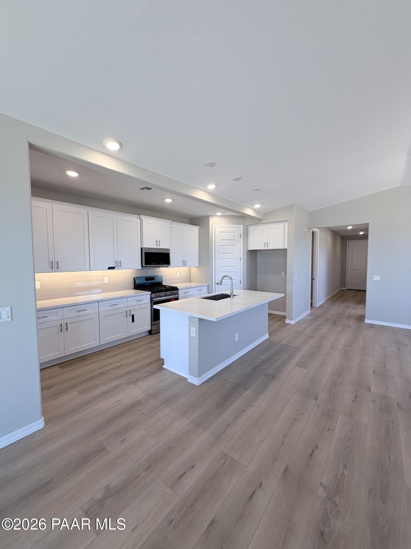 Modern kitchen with white cabinets, quartz island, and wood-look flooring in The Frontier A home at Pronghorn Ranch.