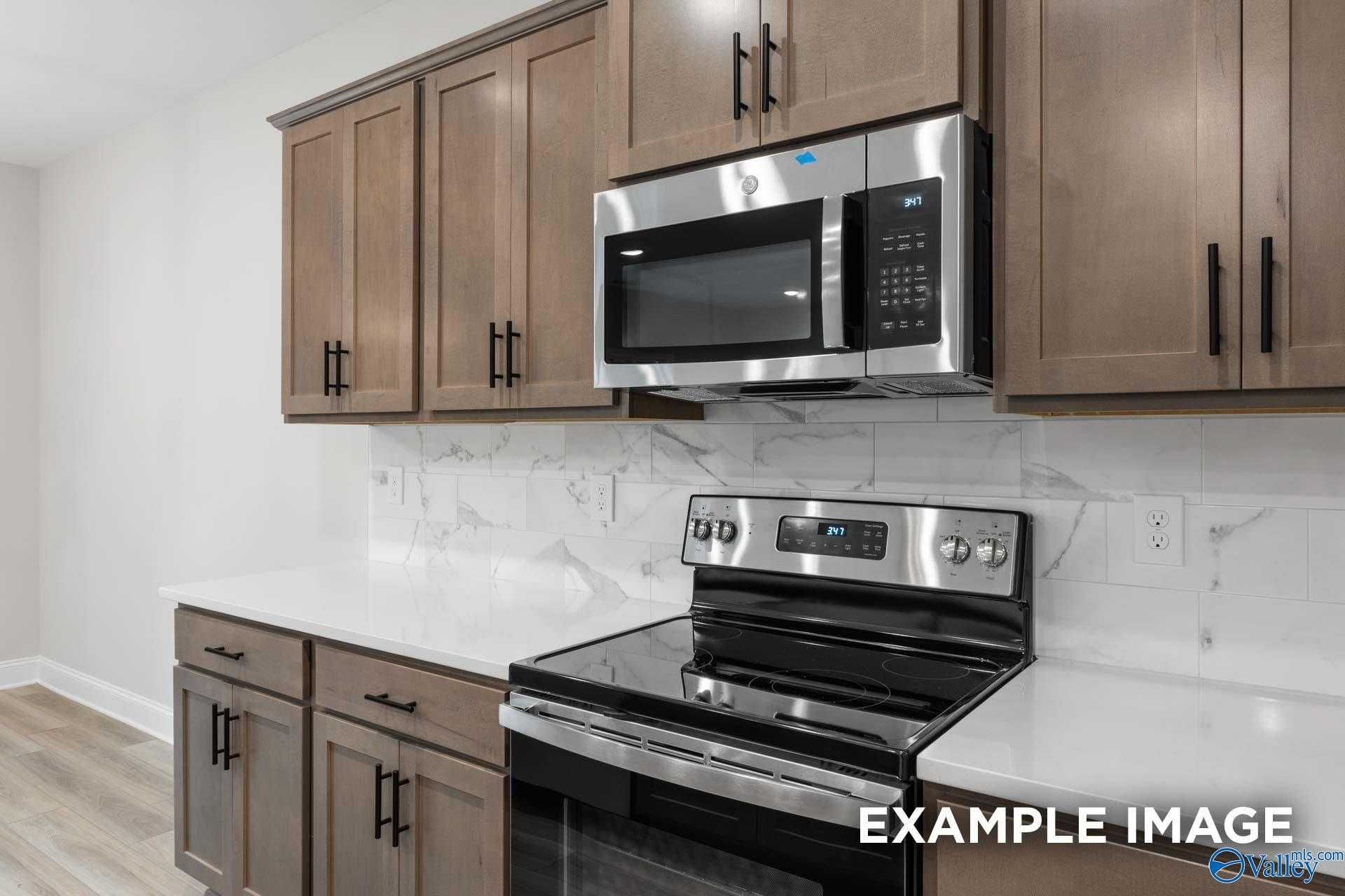 Modern kitchen featuring shaker cabinets, stainless steel microwave and range, subway tile backsplash in Davidson Homes The Camden D, Huntsville AL