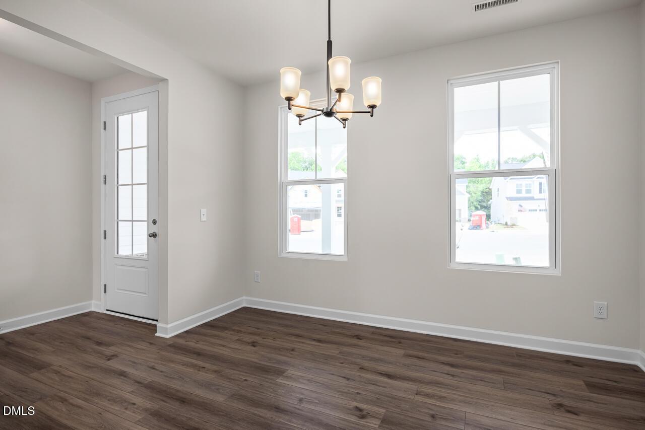Bright dining area with modern chandelier and wood-look flooring in The Willow B by Davidson Homes, Zebulon, North Carolina.