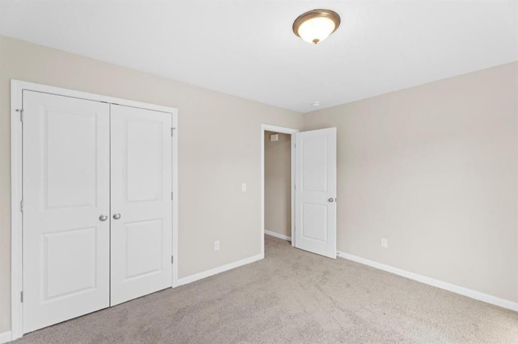 Cozy bedroom with beige walls, white double closet doors, open bathroom entry, and carpeted floor in Davidson Homes The Washington, Phenix City