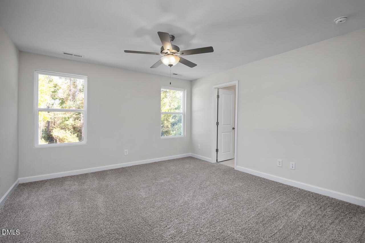 Bright secondary bedroom with neutral walls, plush carpet, ceiling fan, and large windows in Davidson Homes The Grace C, Lillington NC