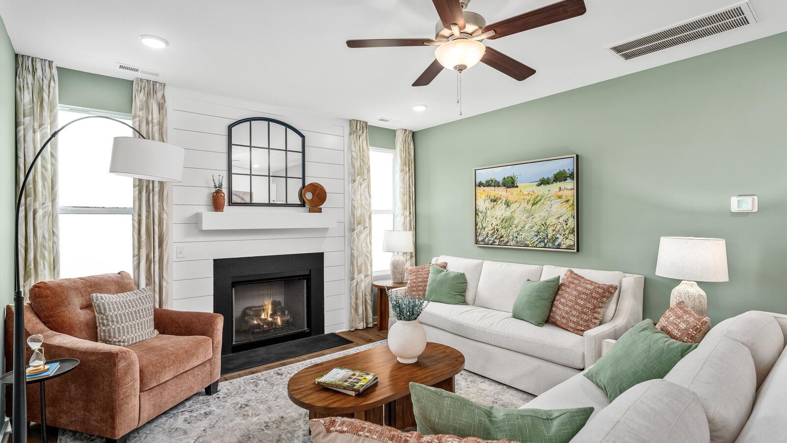 Cozy living room in Calista Farms White House TN with sage green walls gas fireplace white sofa and ceiling fan