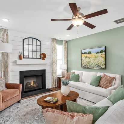 Cozy living room in Calista Farms White House TN with sage green walls gas fireplace white sofa and ceiling fan