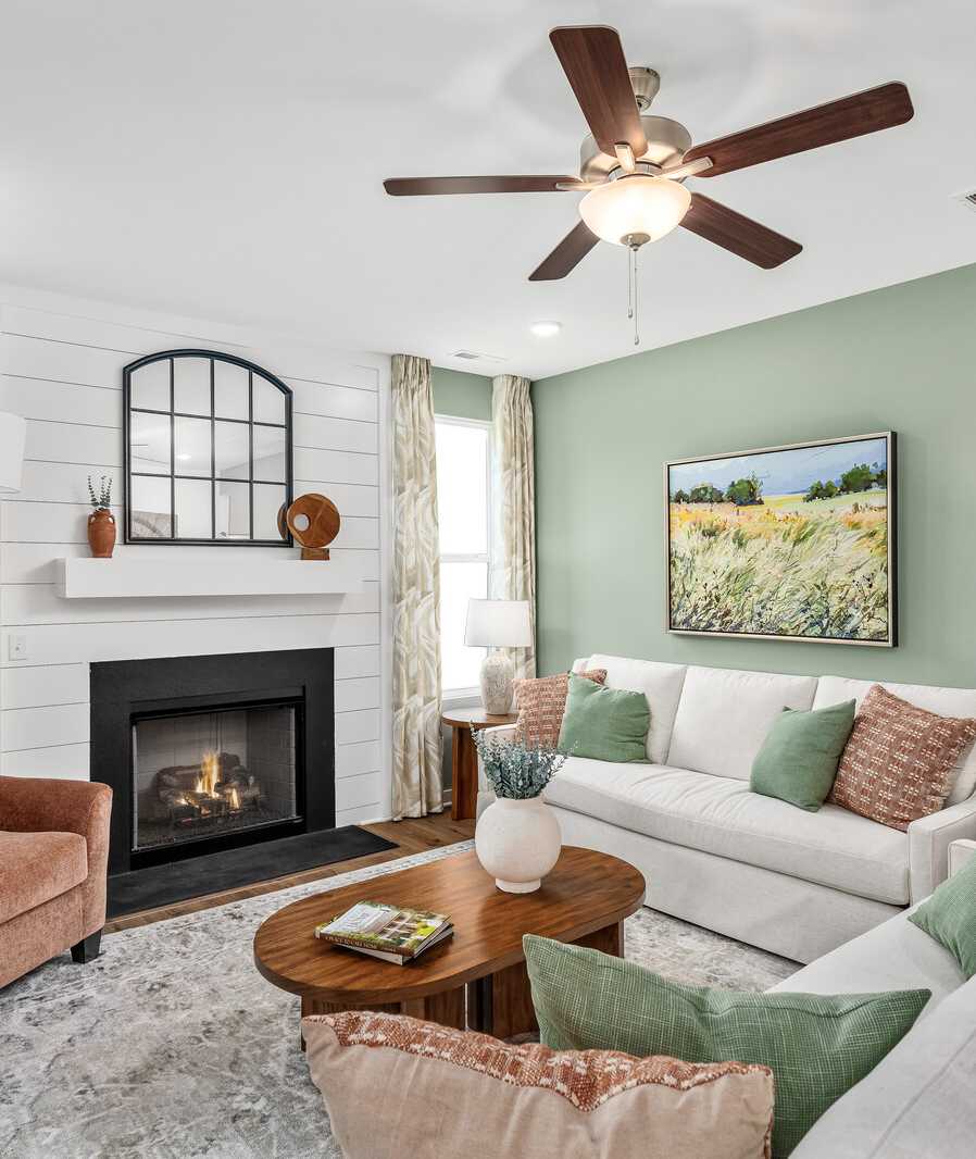 Cozy living room in Calista Farms White House TN with sage green walls gas fireplace white sofa and ceiling fan