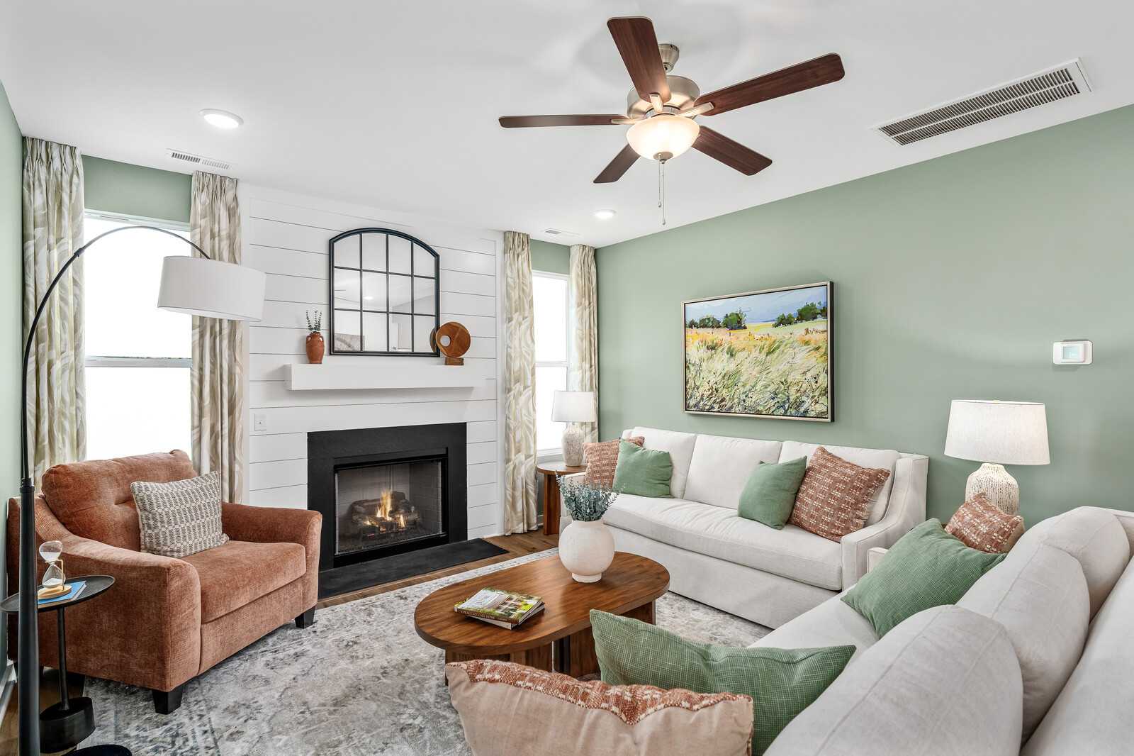 Cozy living room in Calista Farms White House TN with sage green walls gas fireplace white sofa and ceiling fan