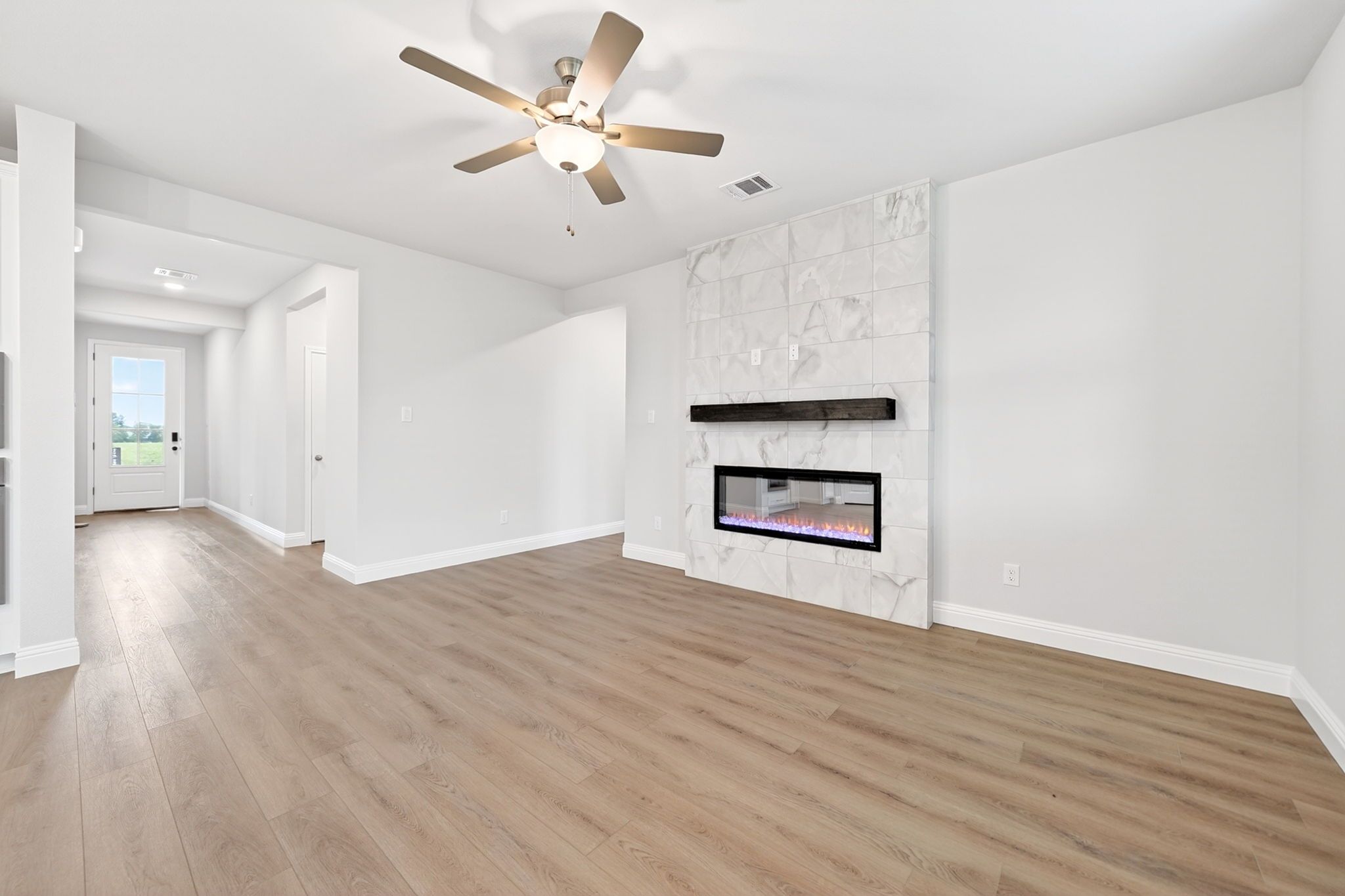 Living room in The Redbud by Davidson Homes featuring a marble tile fireplace, wood-look flooring, and ceiling fan.