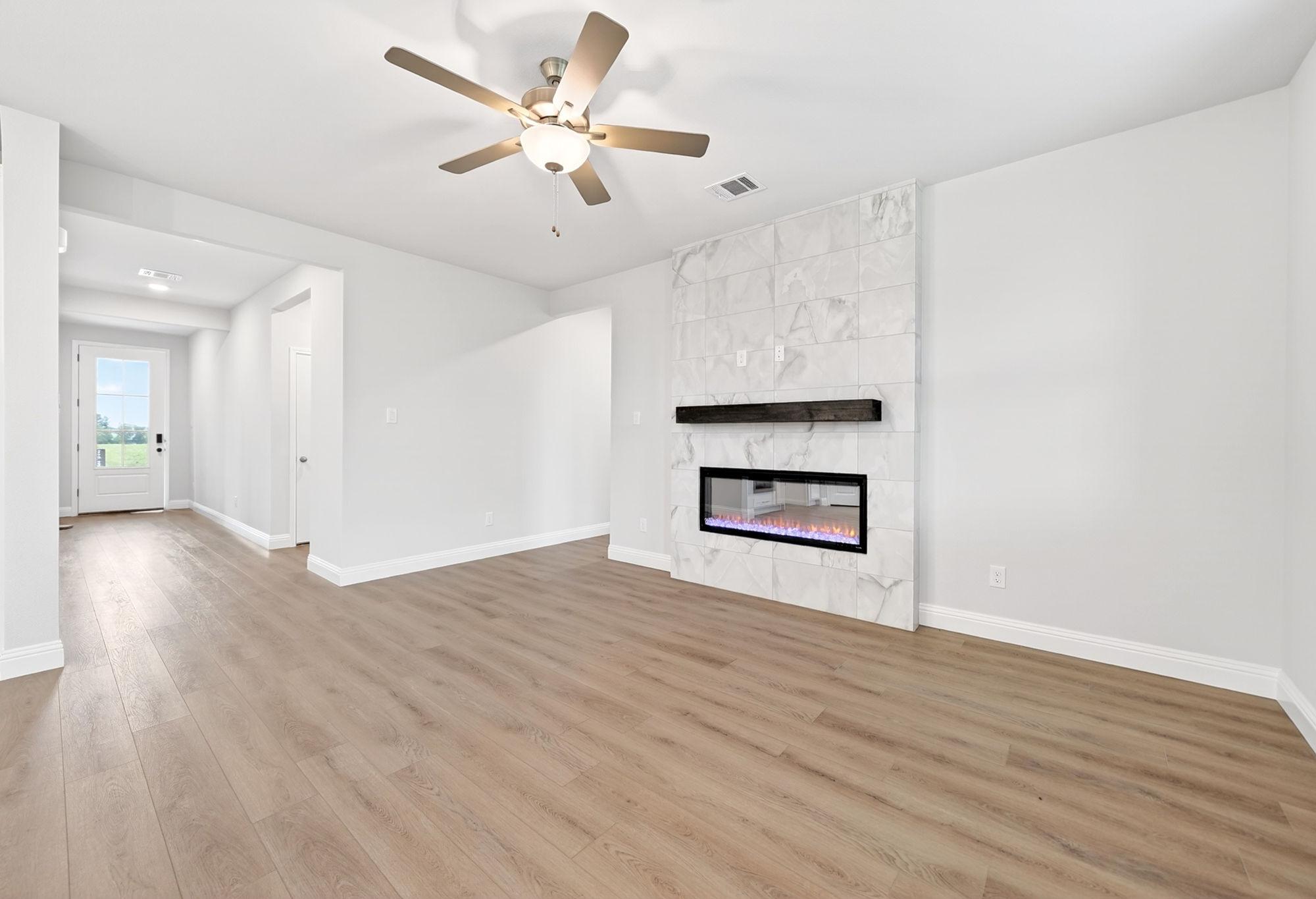 Living room in The Redbud by Davidson Homes featuring a marble tile fireplace, wood-look flooring, and ceiling fan.