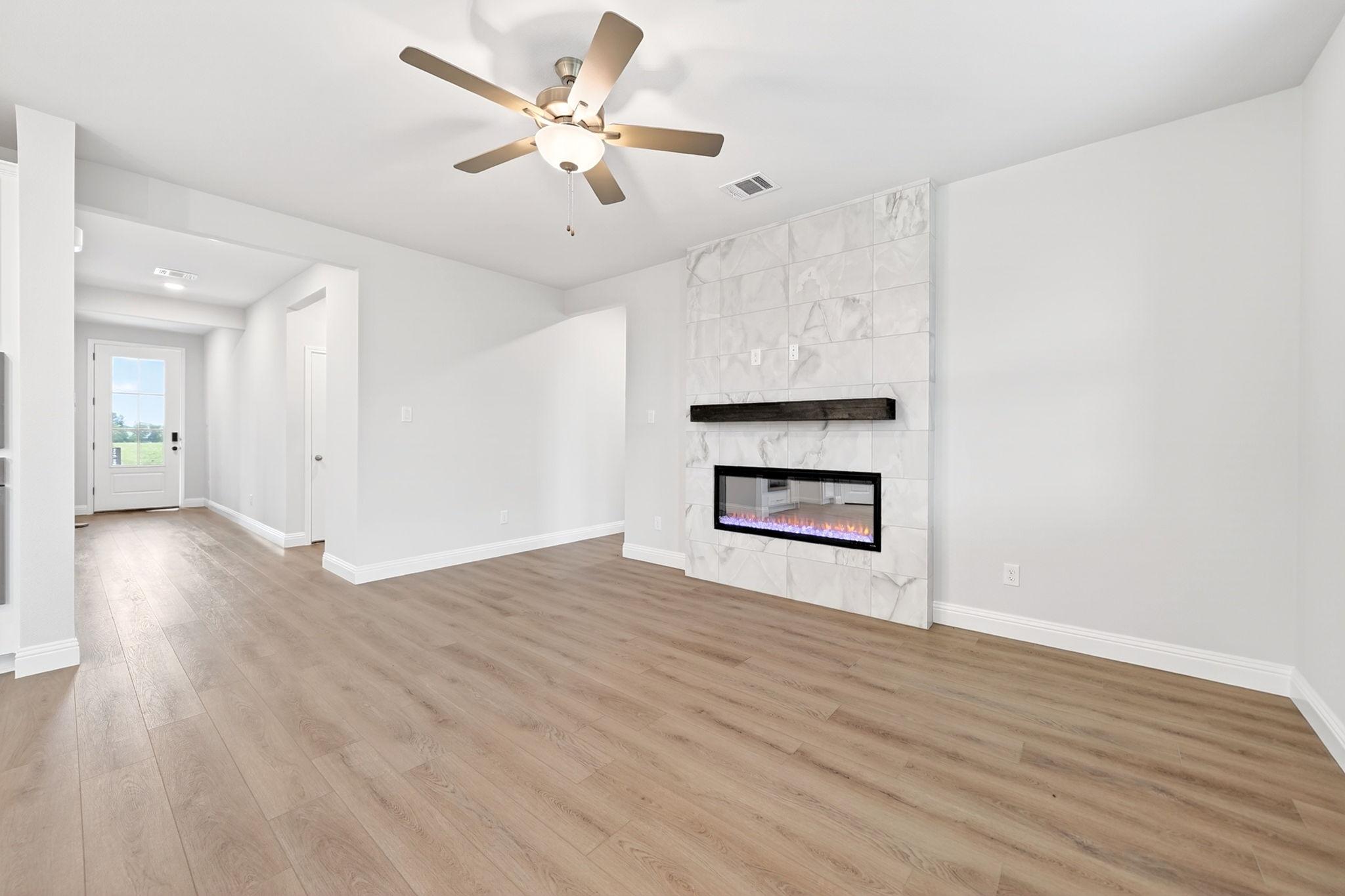 Living room in The Redbud by Davidson Homes featuring a marble tile fireplace, wood-look flooring, and ceiling fan.