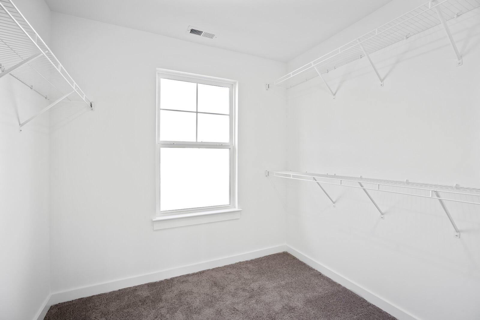 Spacious walk-in closet with white wire shelving, hanging rods, and window in Davidson Homes The Willow, Gallatin, TN