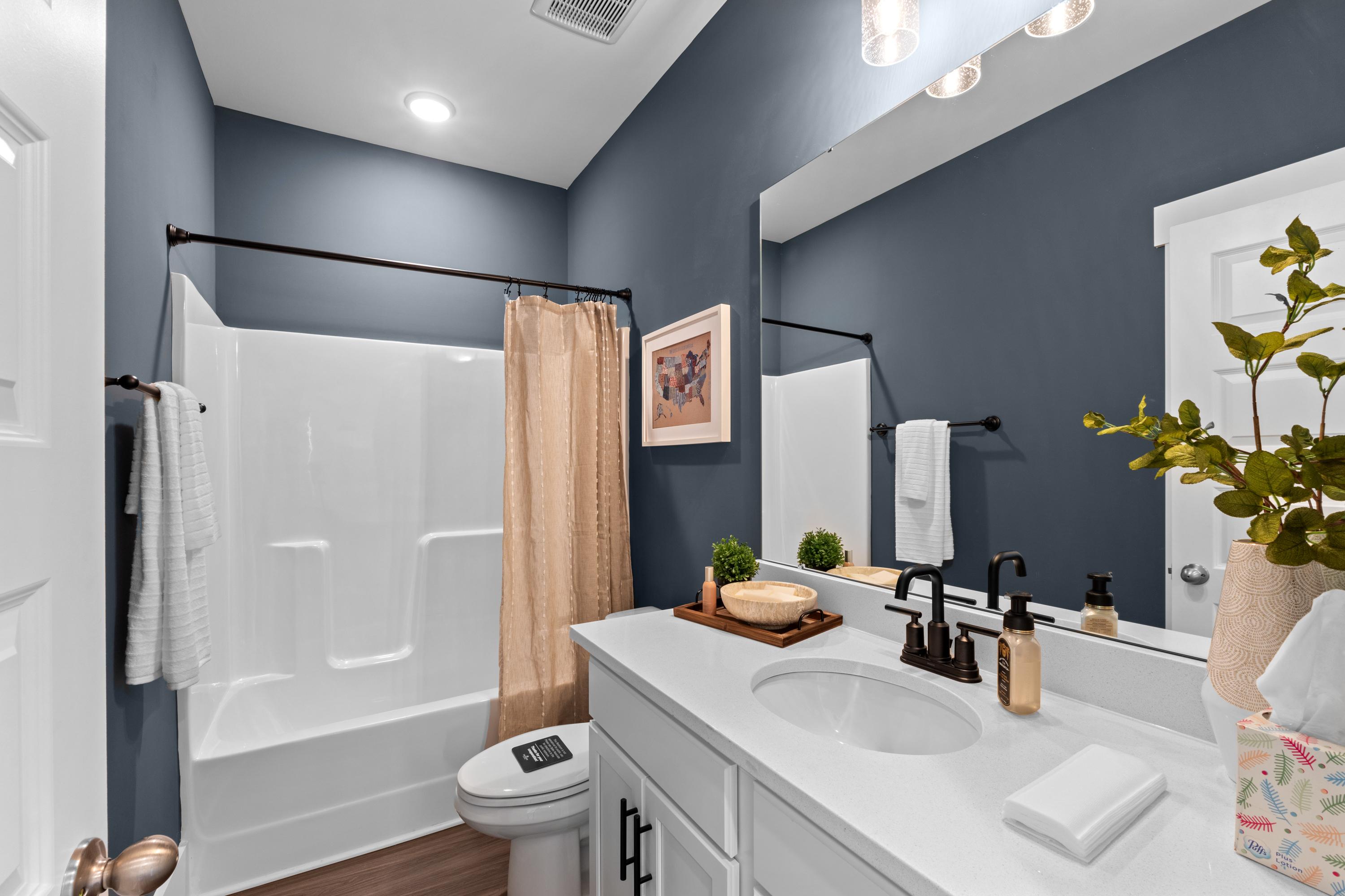Modern bathroom at Ivy Hills in Toney Alabama with navy walls white vanity subway tile shower and hardwood floors