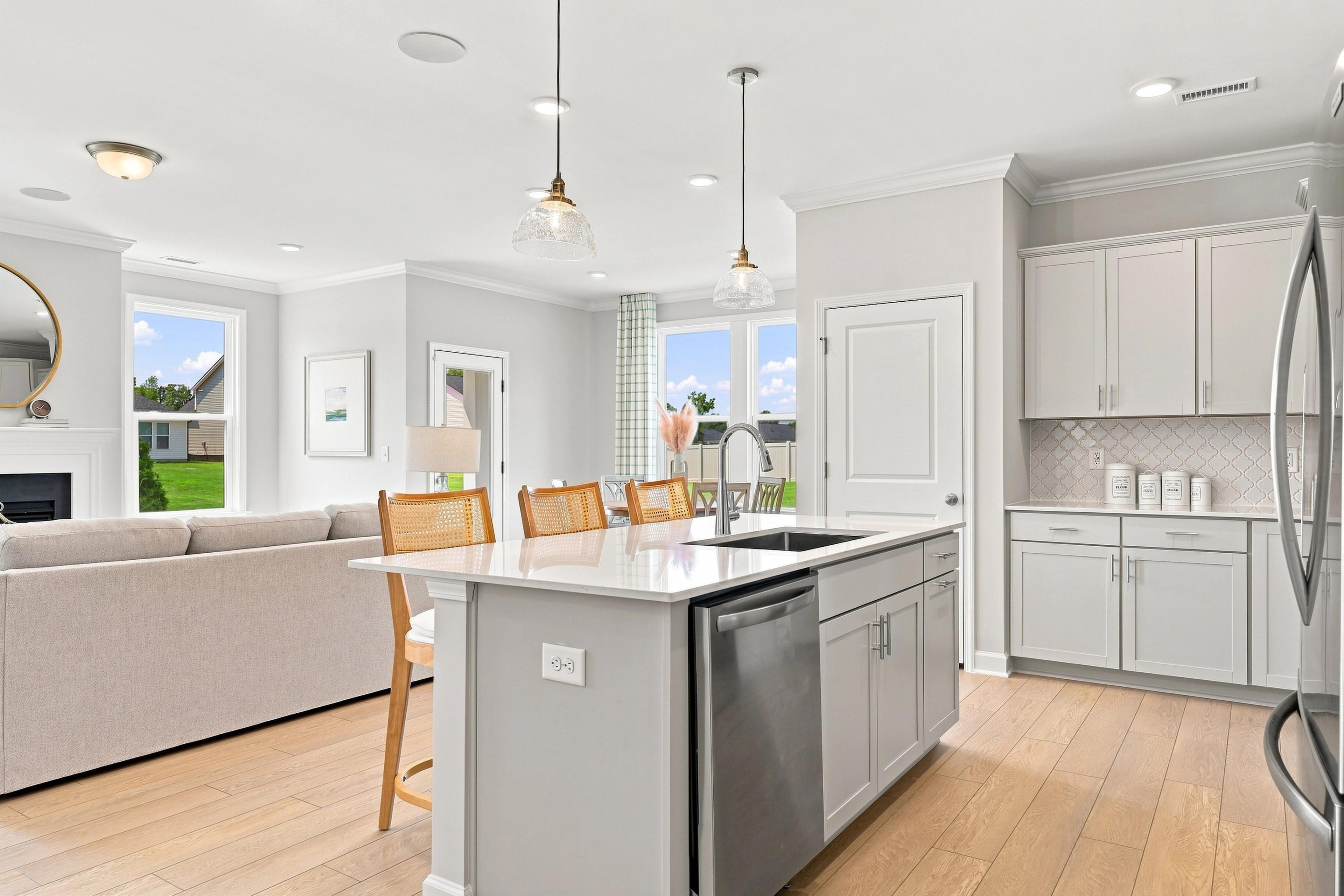 Open-concept kitchen and living area in The Daphne D featuring a large island, modern cabinetry, and light wood flooring.
