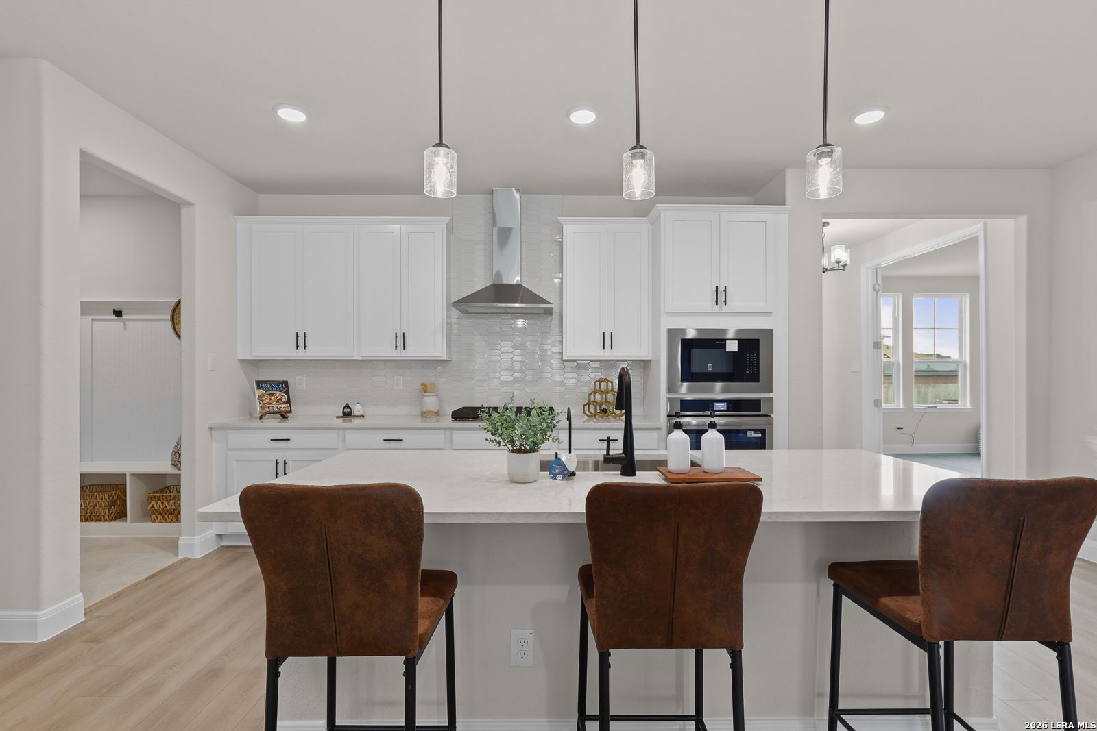 Modern white kitchen with quartz island, stainless double ovens, pendant lights in The Lanier G by Davidson Homes, Castroville, TX