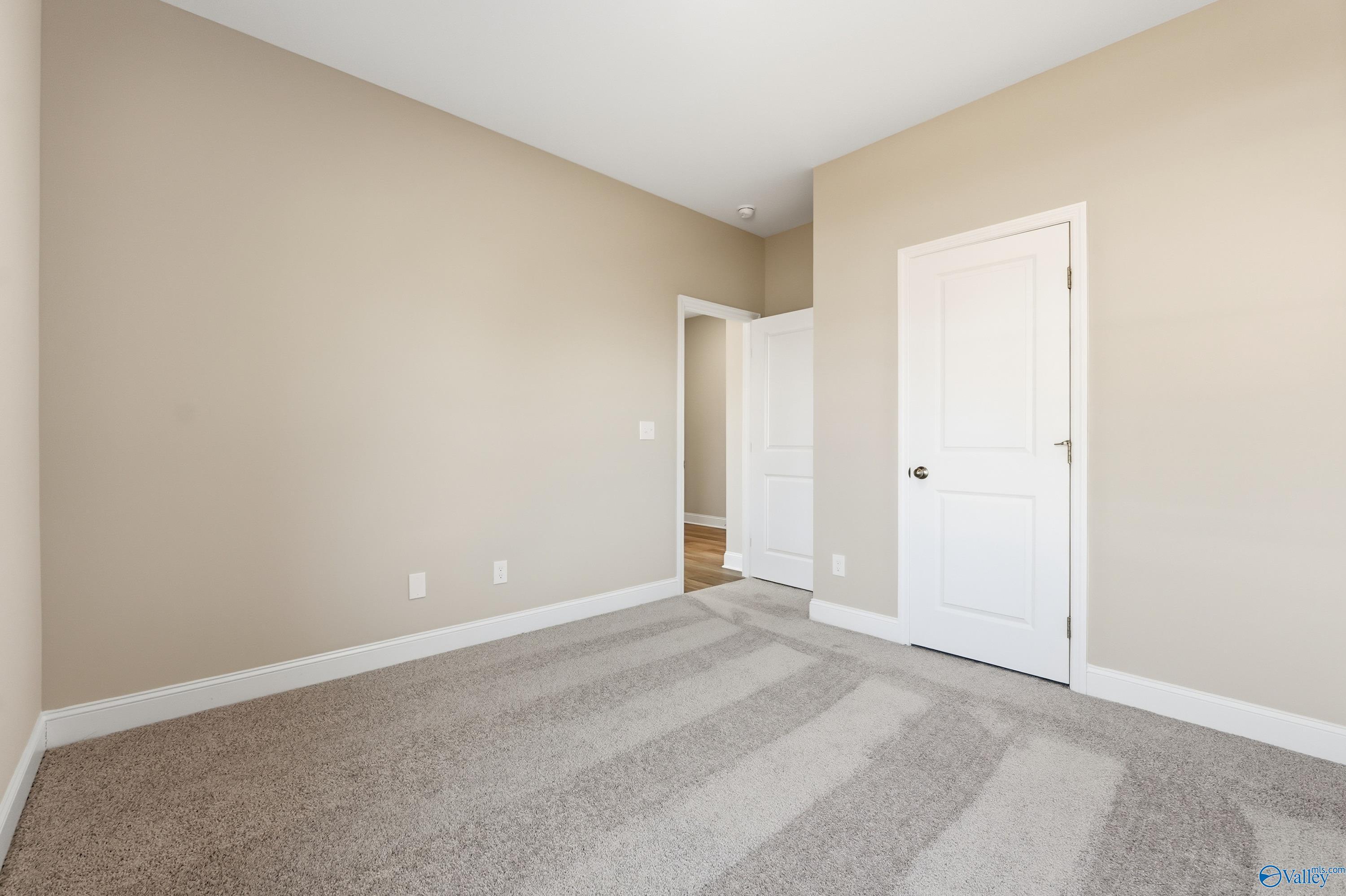 Bright secondary bedroom with beige walls, white doors, plush carpet in Davidson Homes The Franklin C, New Market, Alabama