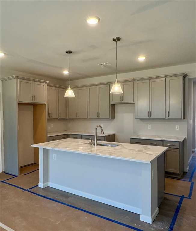 Modern kitchen with light gray cabinets, white quartz island, pendant lights, and sink in The Luna B by Davidson Homes, Opelika, Alabama