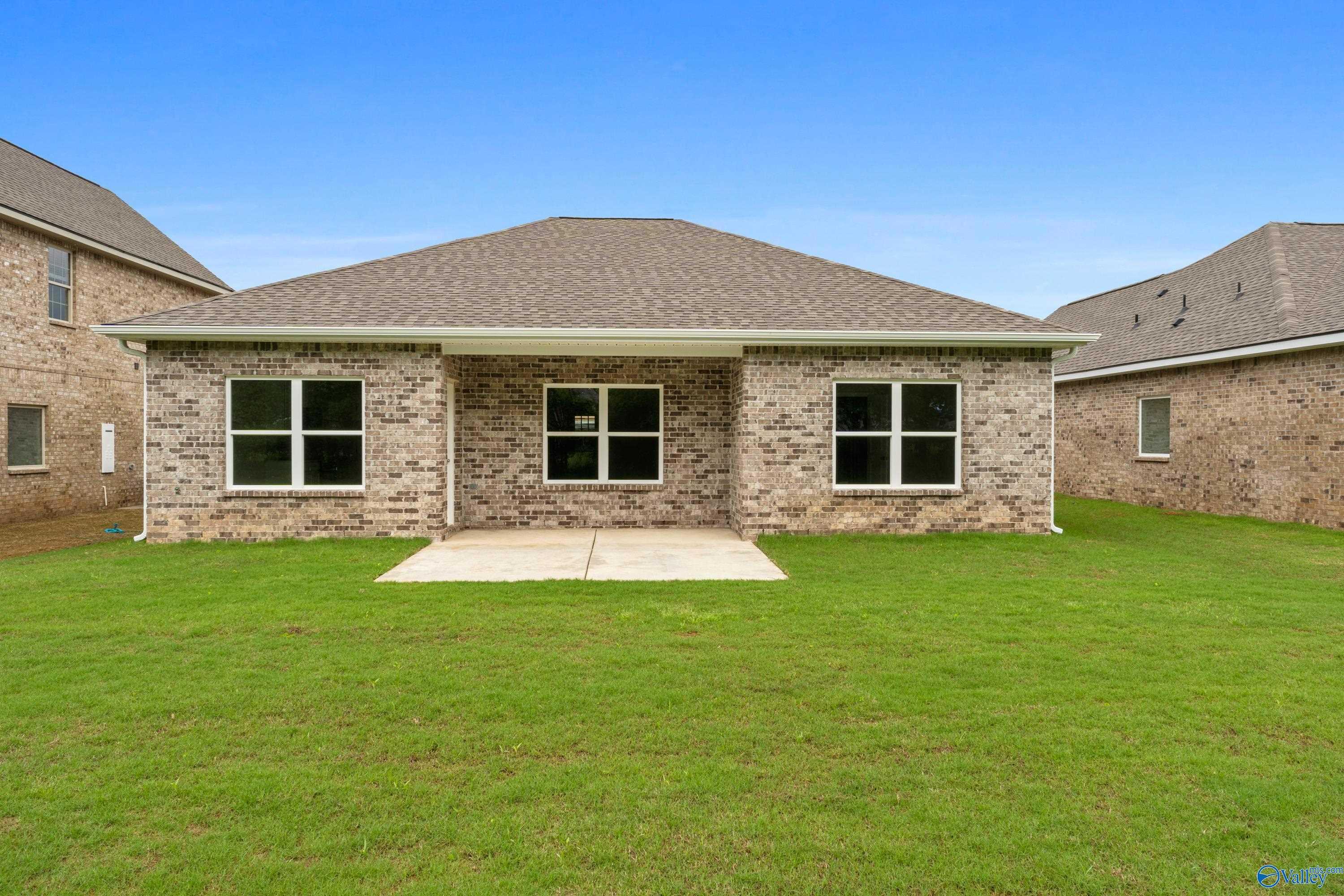 Rear view of The Asheville C brick home by Davidson Homes: covered patio, double windows, lush green lawn in Jaguar Hills, Huntsville AL