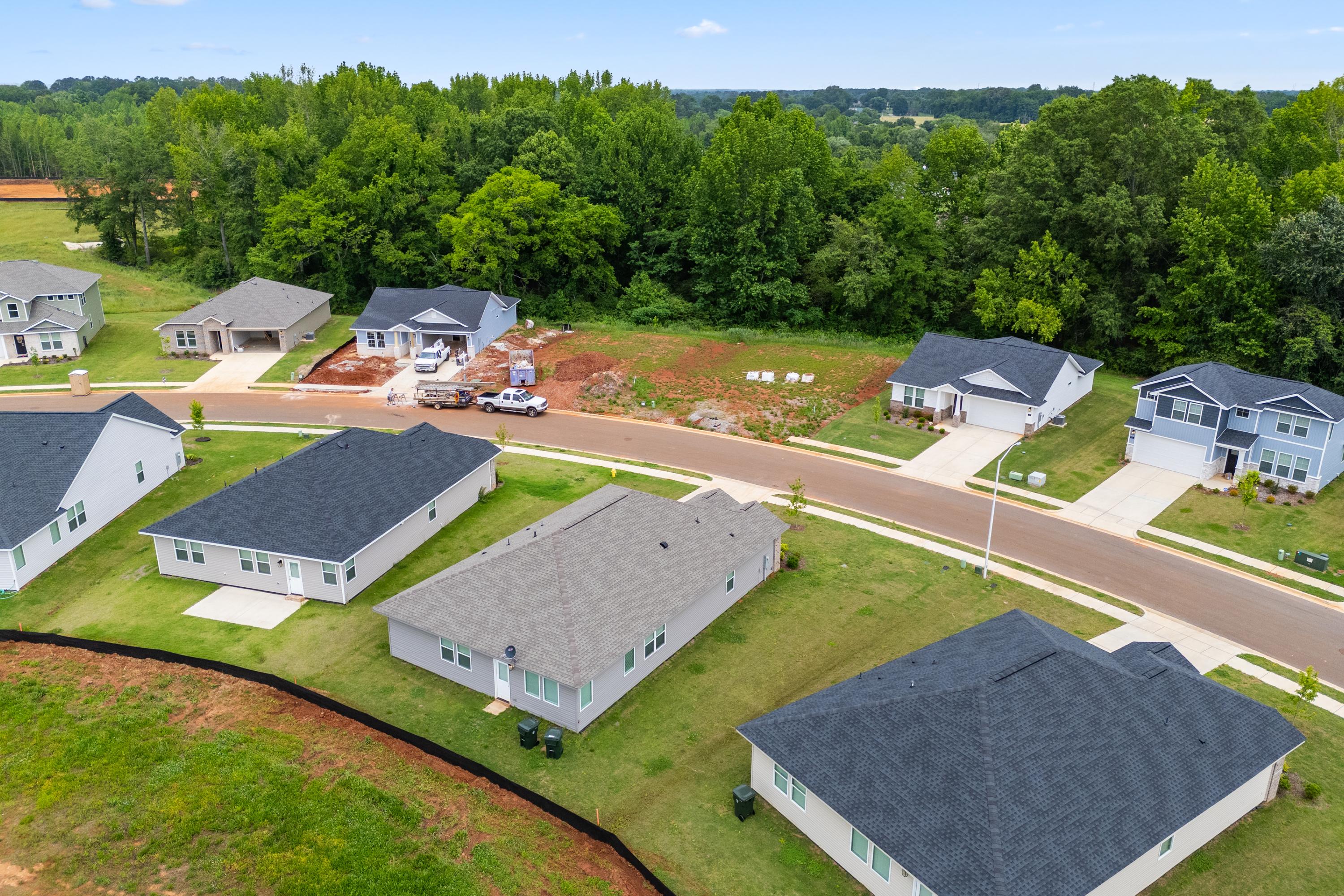 Aerial view of new construction homes in Forest Glen Hazel Green Alabama with shingle roofs green lawns and wooded surroundings