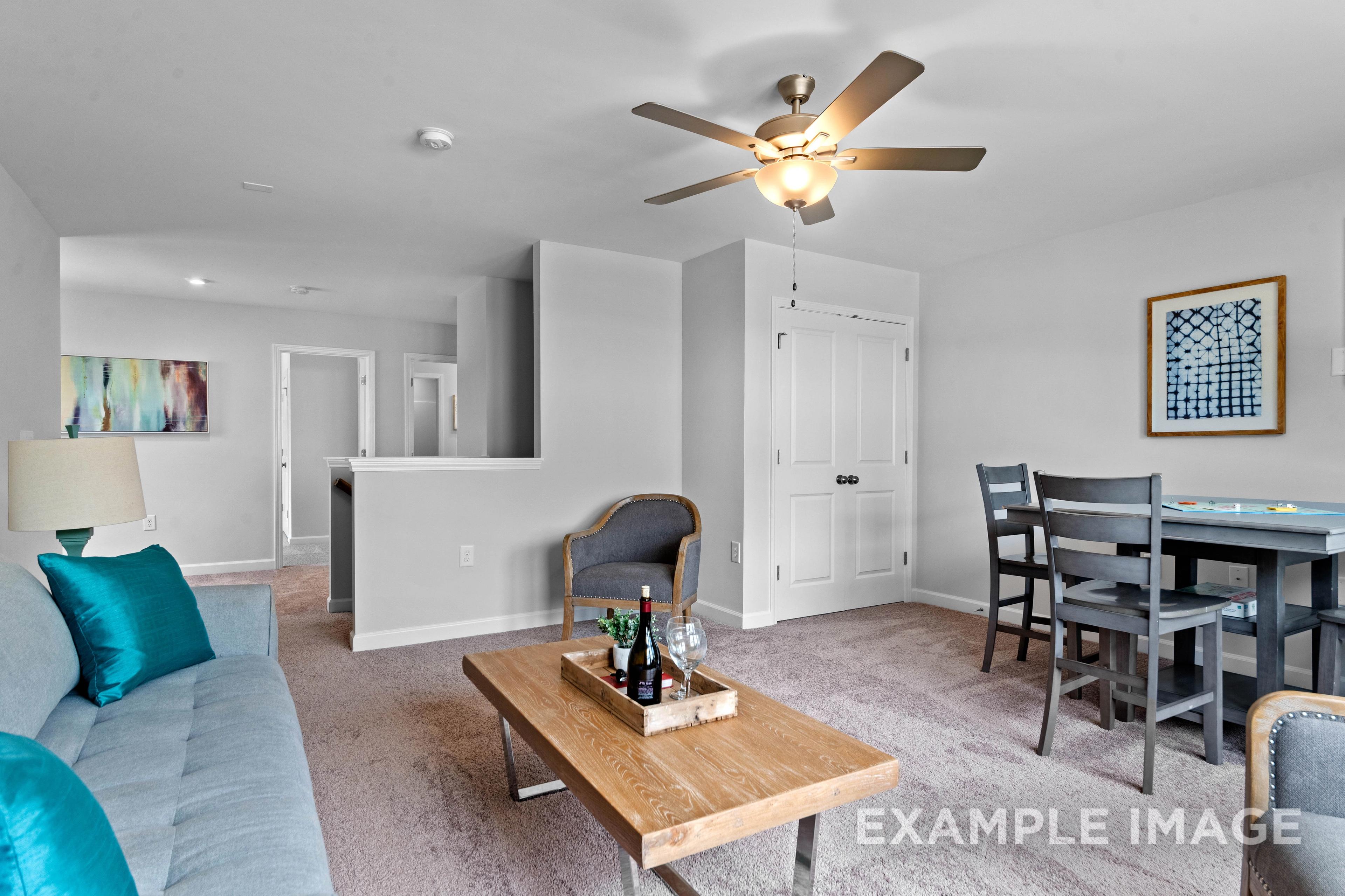 Spacious living room in The Ash home design featuring gray sofa, wooden coffee table, dining area, and ceiling fan