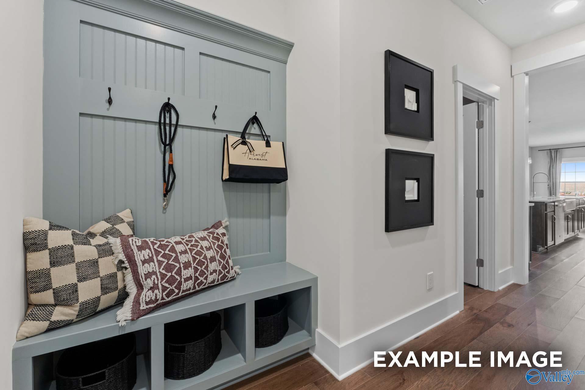 Cozy entryway bench with blue shiplap backing, coat hooks, patterned pillows, and storage baskets in Davidson Homes The Finleigh, Huntsville