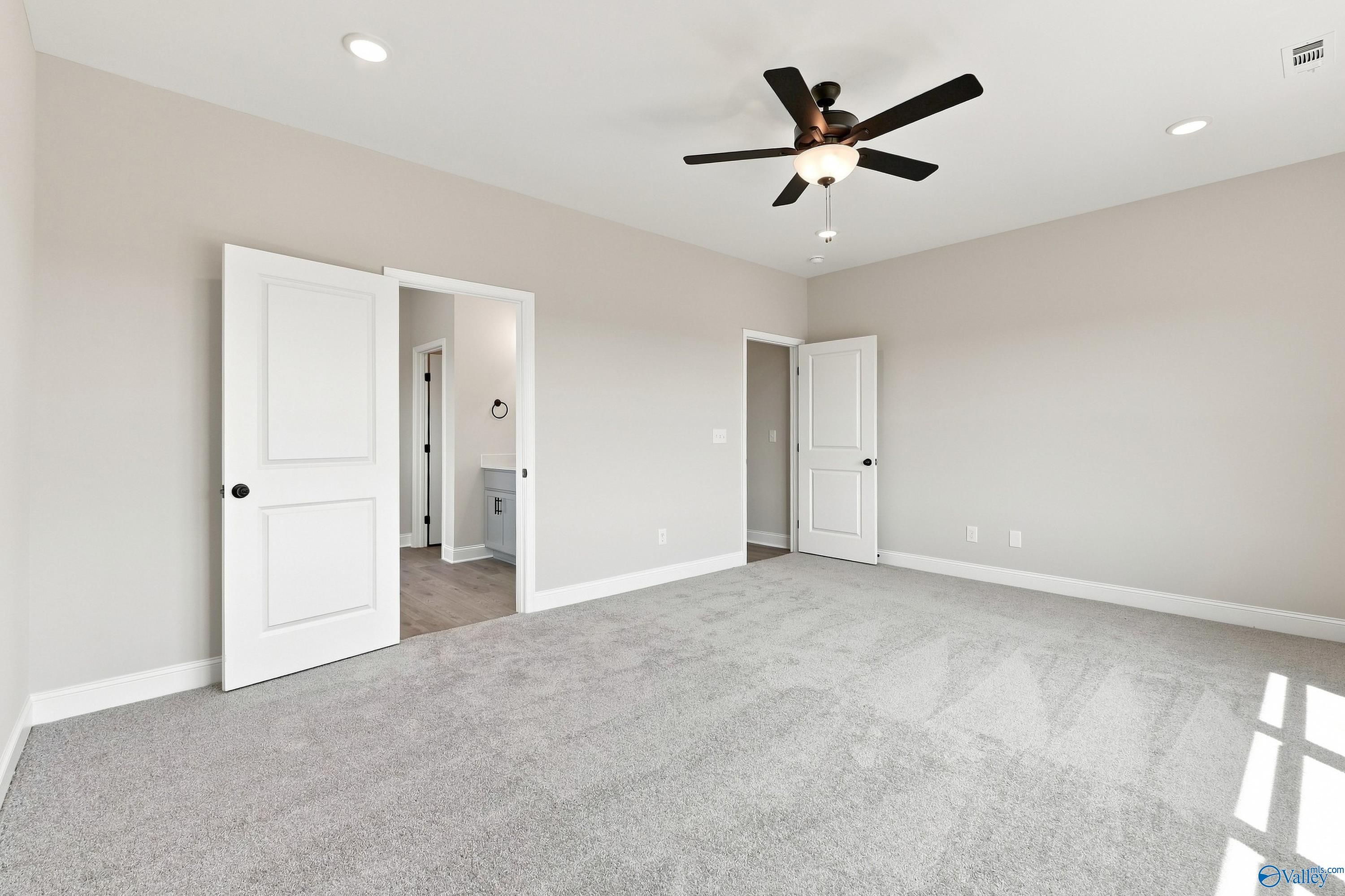Spacious primary bedroom with ceiling fan and carpet in Davidson Homes Montgomery D plan, Anderson Farm, Athens, Alabama