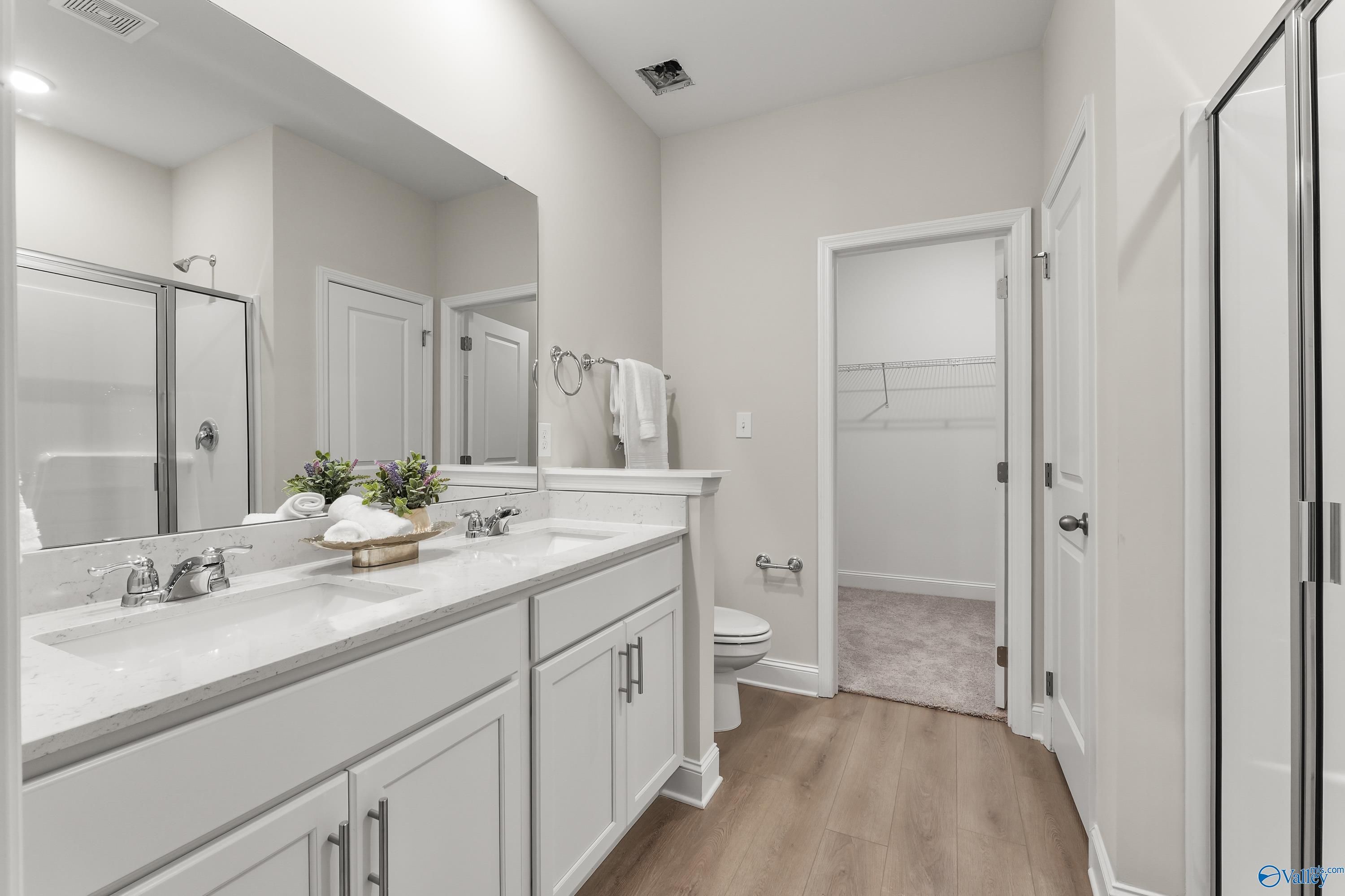 Elegant master bathroom with double vanity, frameless shower, and walk-in closet in Davidson Homes Asheville C, Huntsville AL