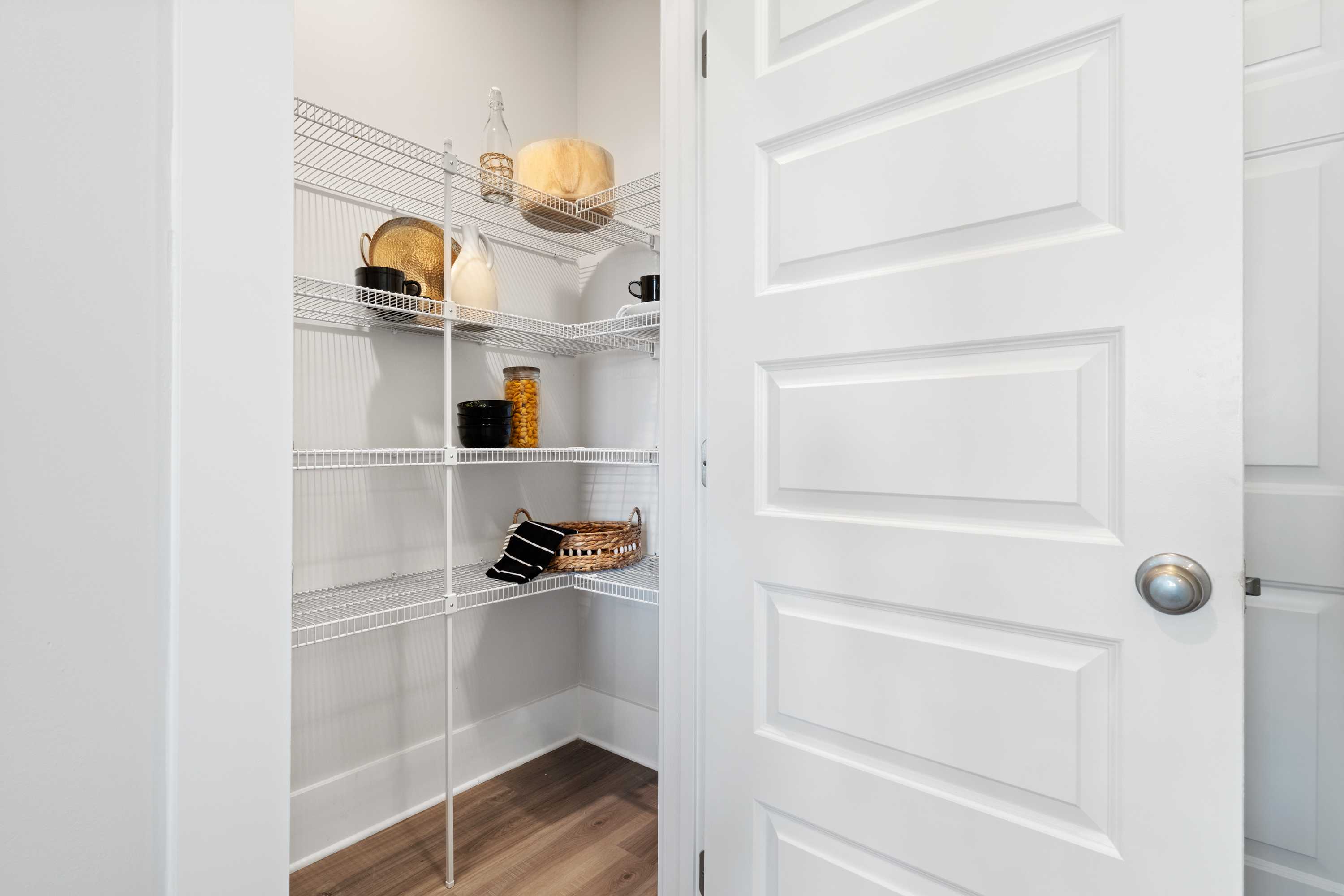 Spacious walk-in pantry in The Chelsea A home with white wire shelves stocked with jars, baskets, and cookware