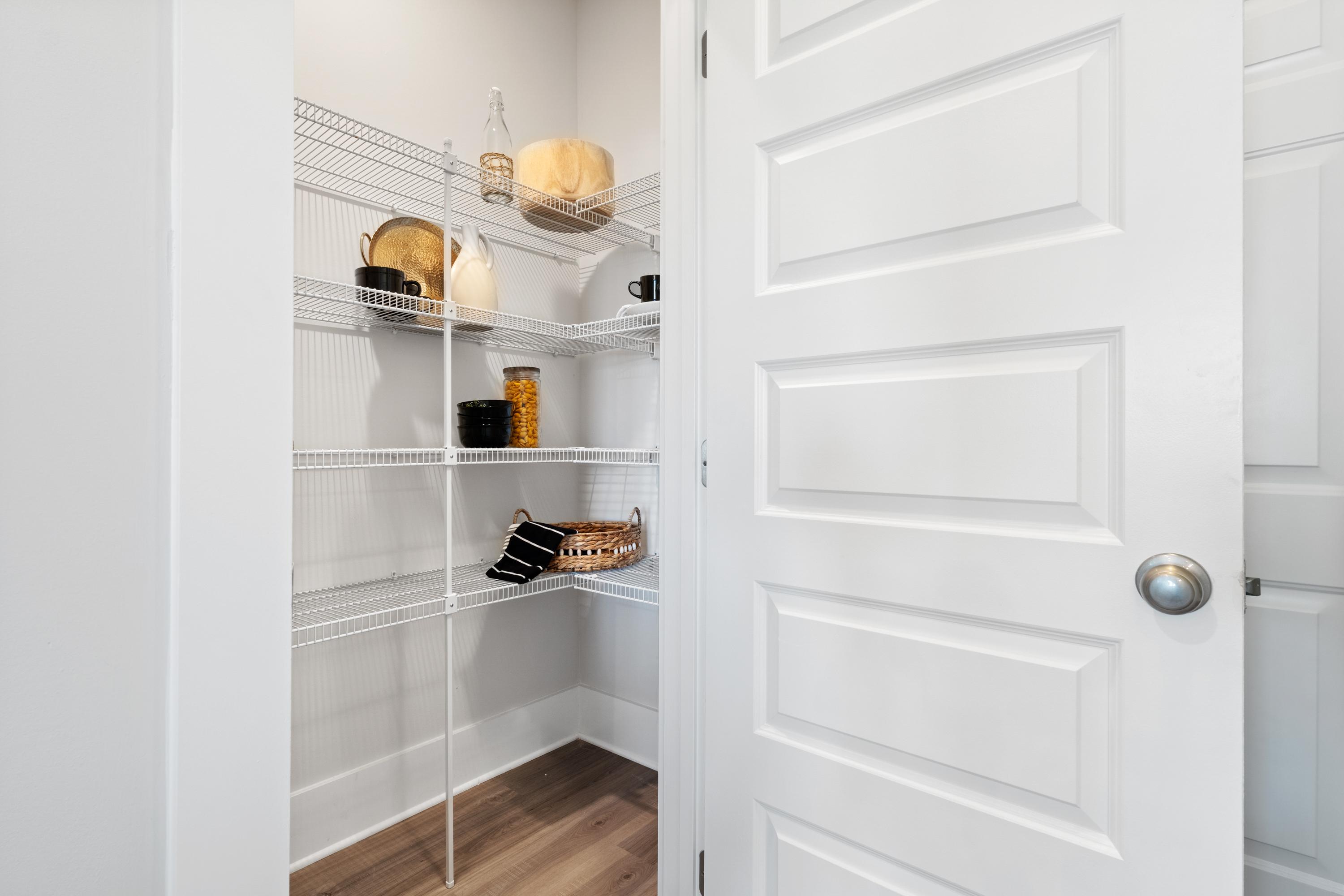Spacious walk-in pantry in The Chelsea A home with white wire shelves stocked with jars, baskets, and cookware