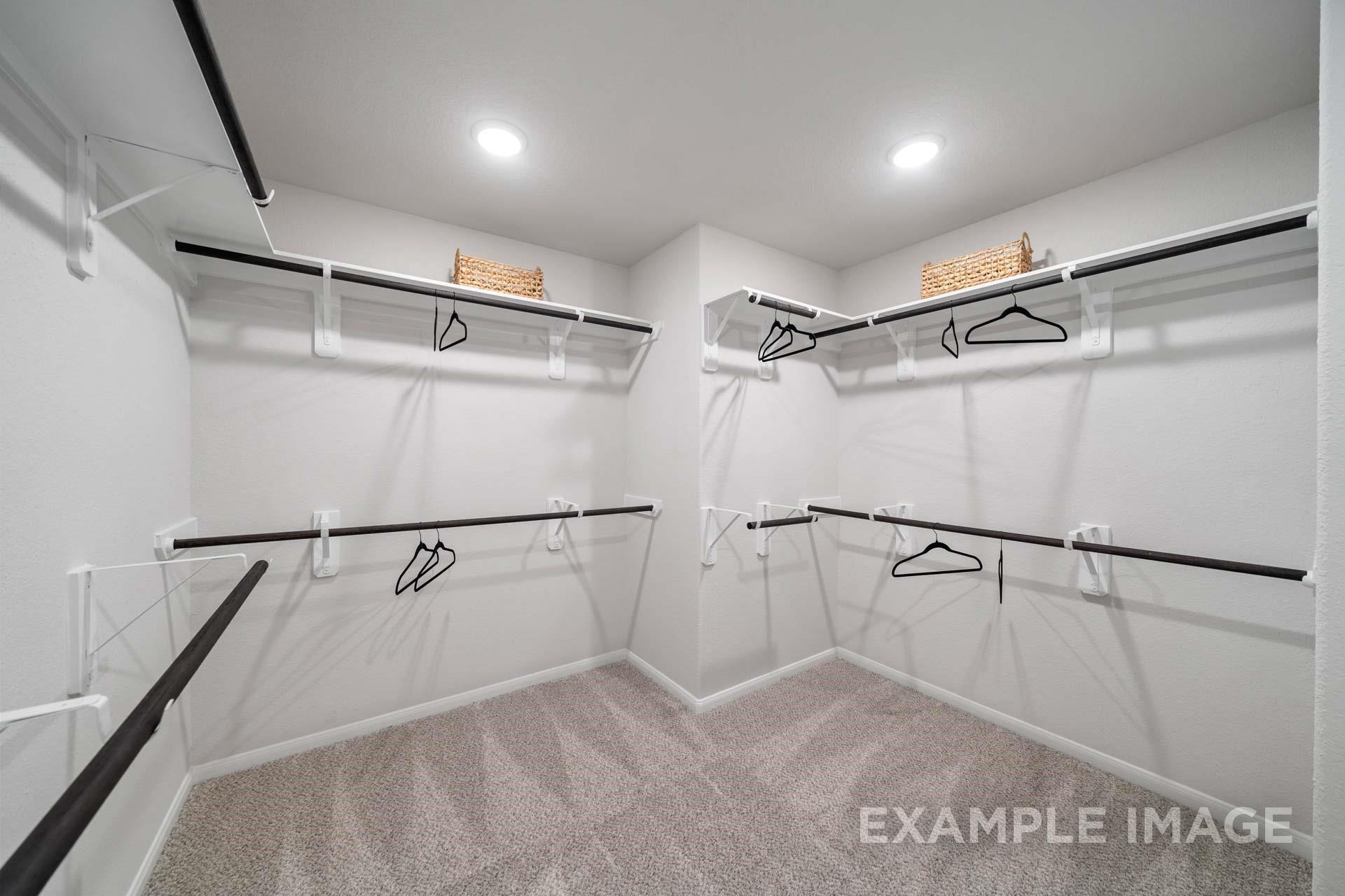 Spacious walk-in closet with dual hanging rods, white shelving, and recessed lighting in The Acadia A floor plan at Lago Mar, Texas City