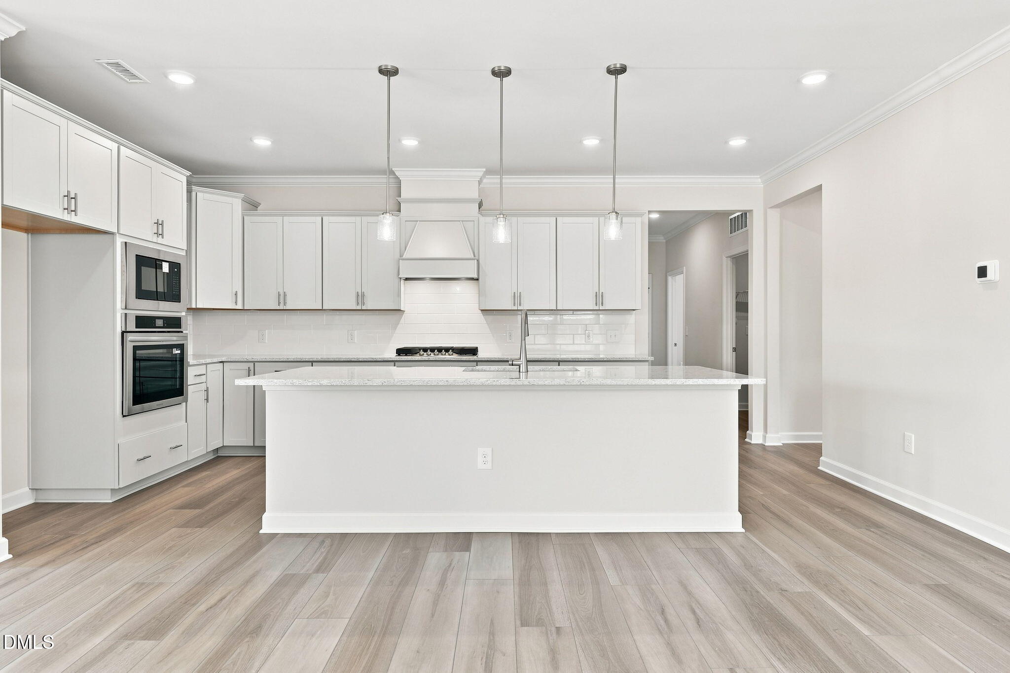 Modern kitchen with white cabinets, island, and stainless steel appliances in The Magnolia B at Retreat at North Main.
